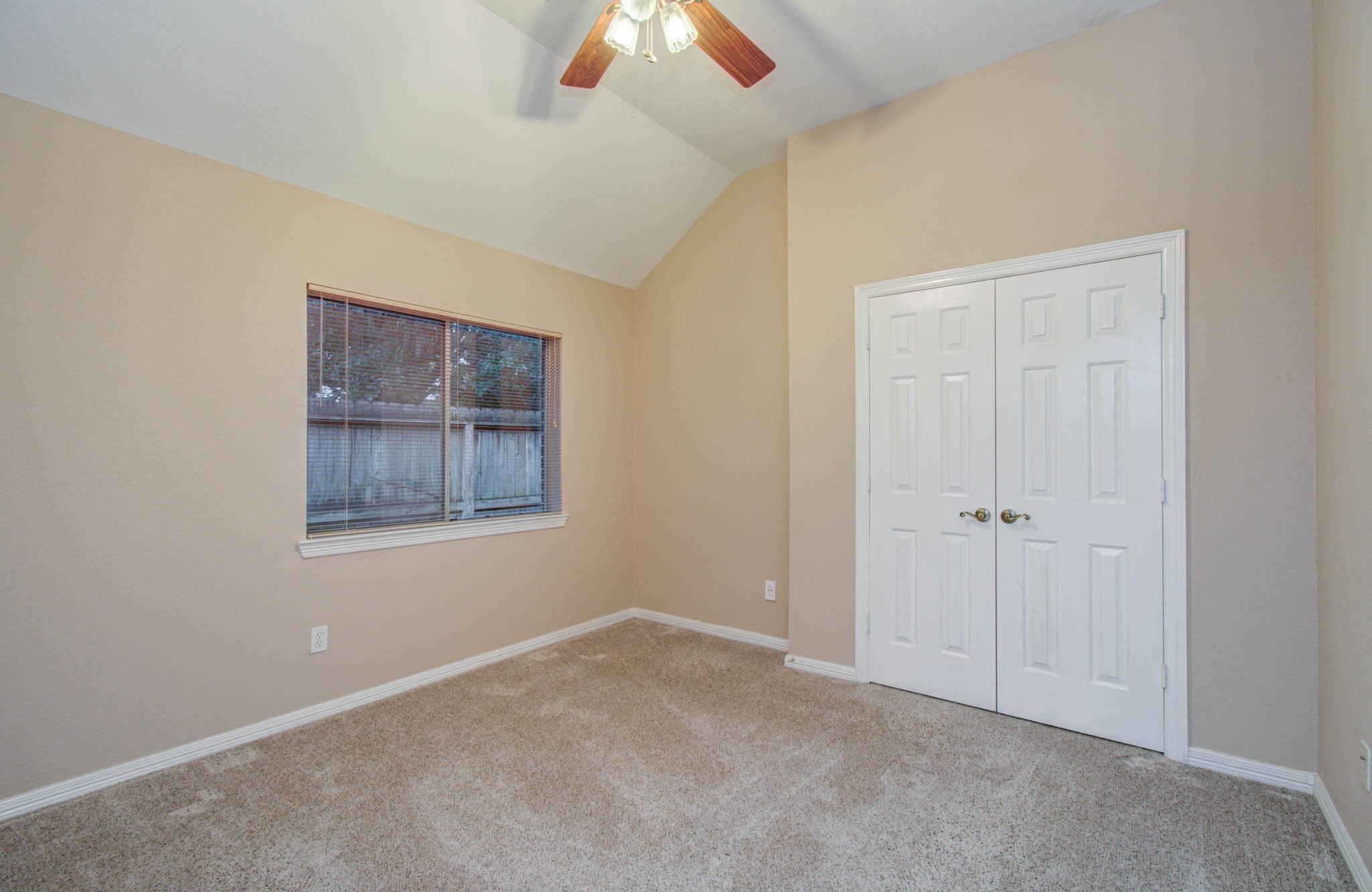 Bright and cozy room featuring a vaulted ceiling, soft carpet, a large window, and a spacious double-door closet.