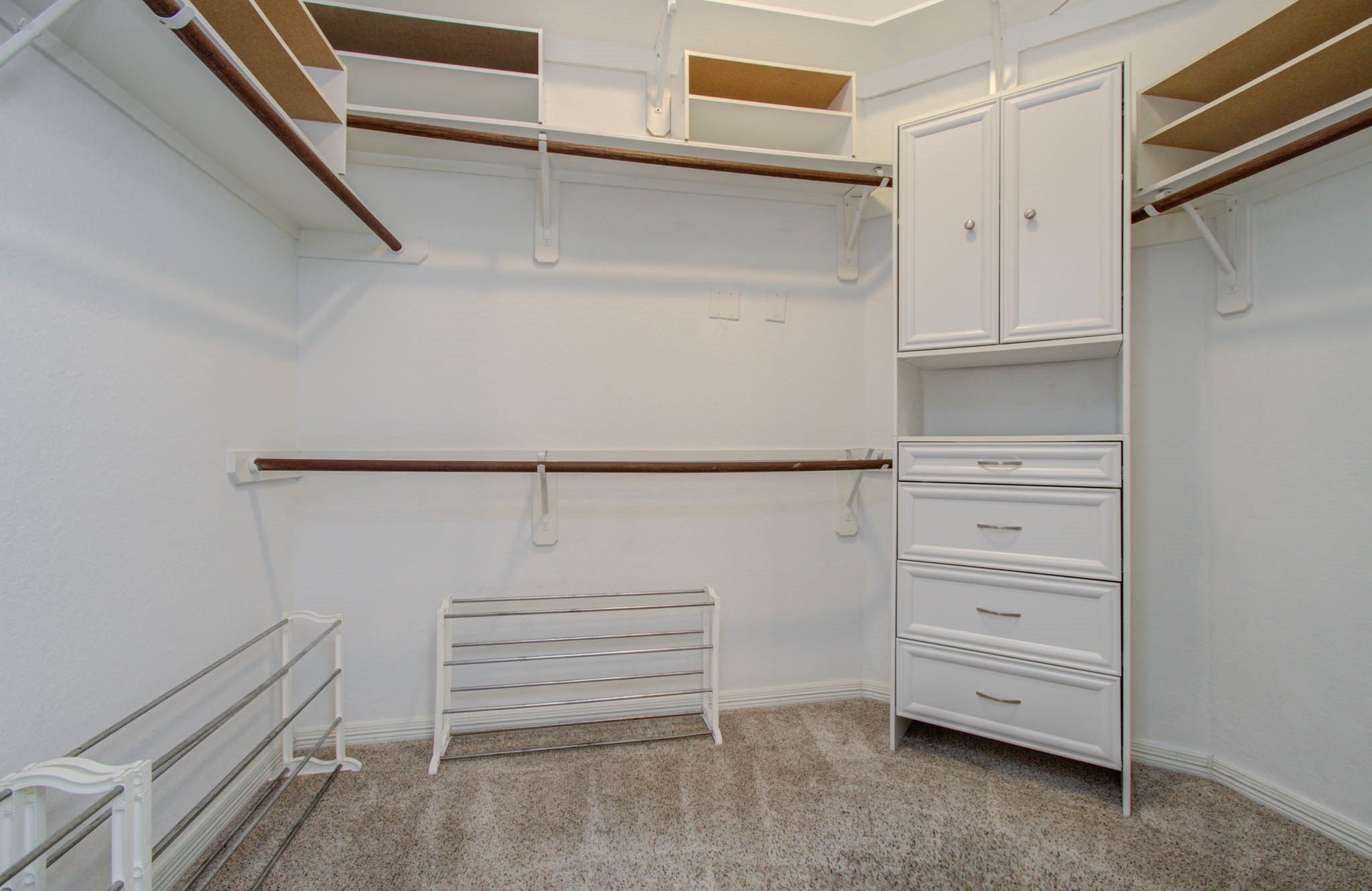 Spacious walk-in closet featuring ample shelving, hanging space, and a built-in drawer unit for organized storage.