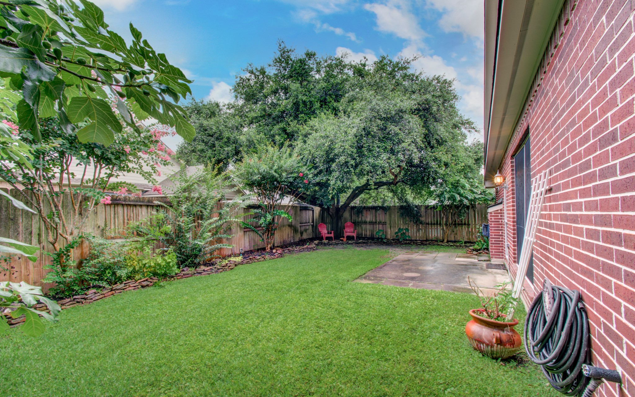 Charming backyard with lush green lawn, mature trees, and a cozy patio perfect for relaxing.