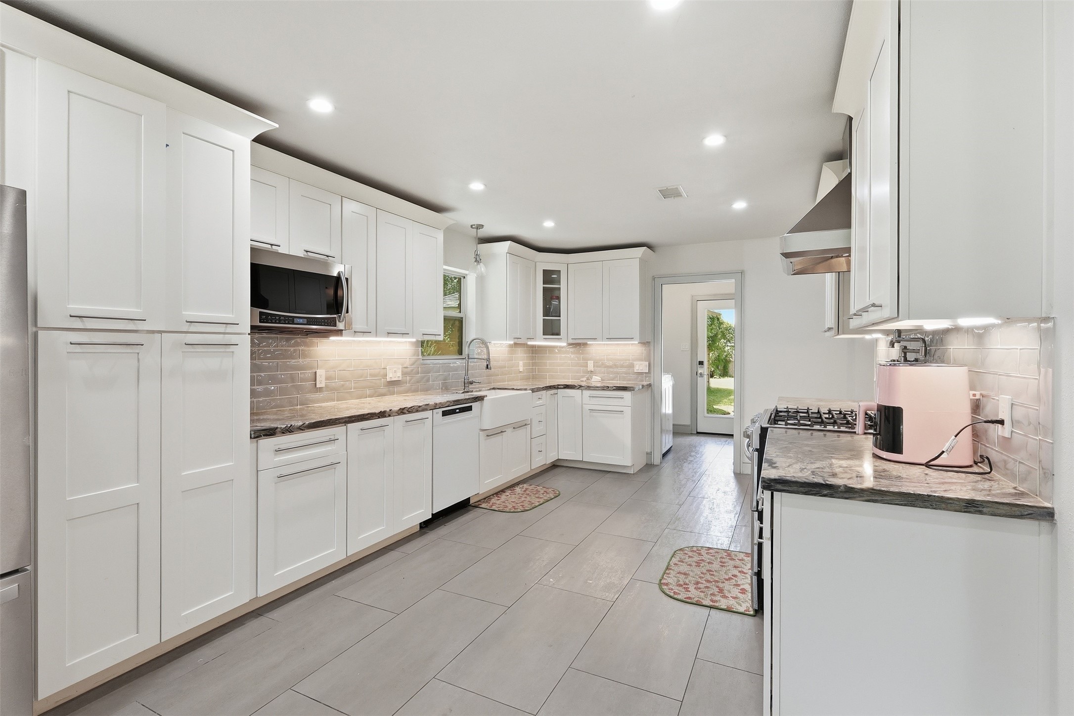 Bright, updated kitchen featuring abundant cabinetry, generous counter space, stainless steel appliances, and a farmhouse sink.