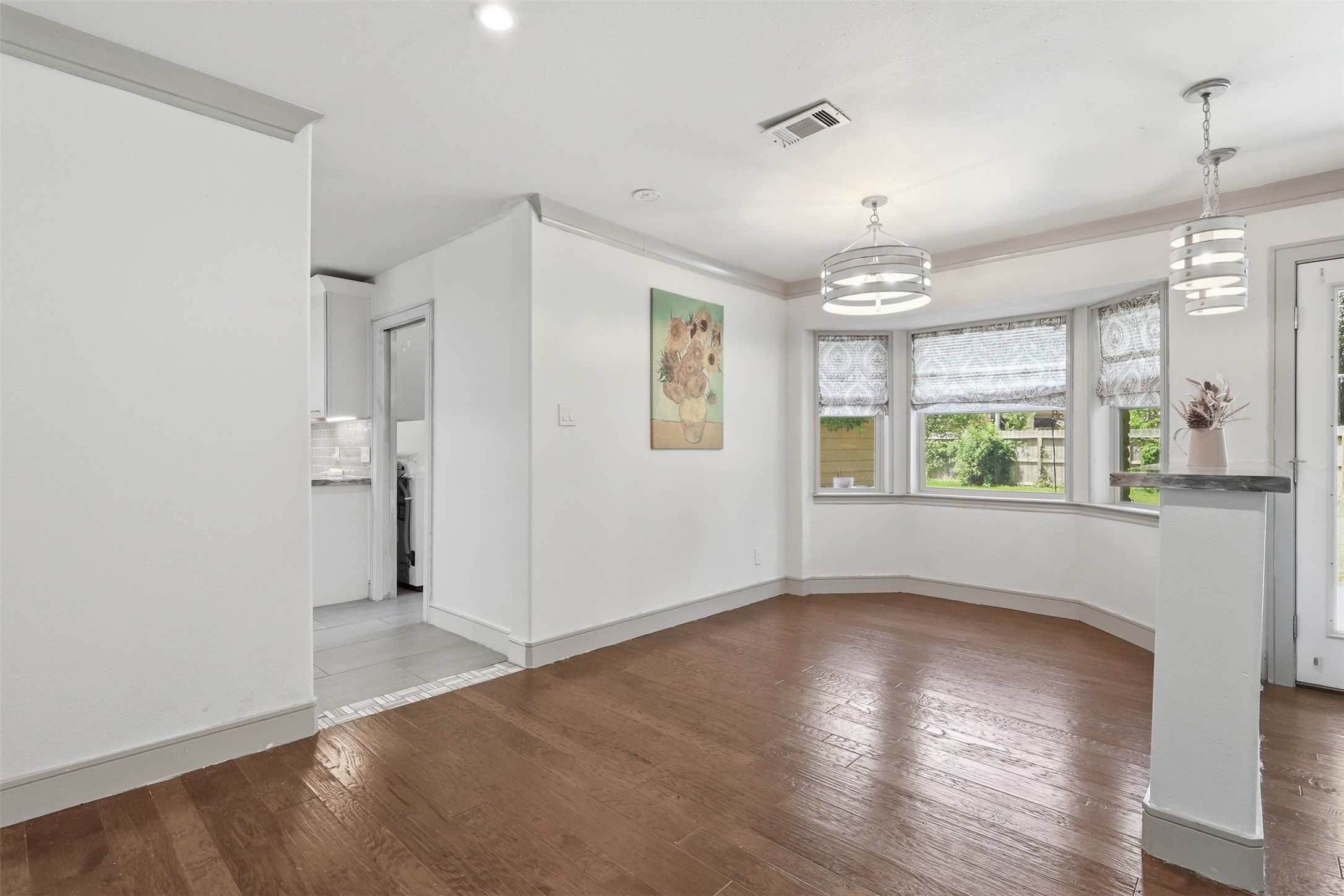 Light-filled breakfast area with beautiful bay windows, hardwood floors, and easy access to the backyard.