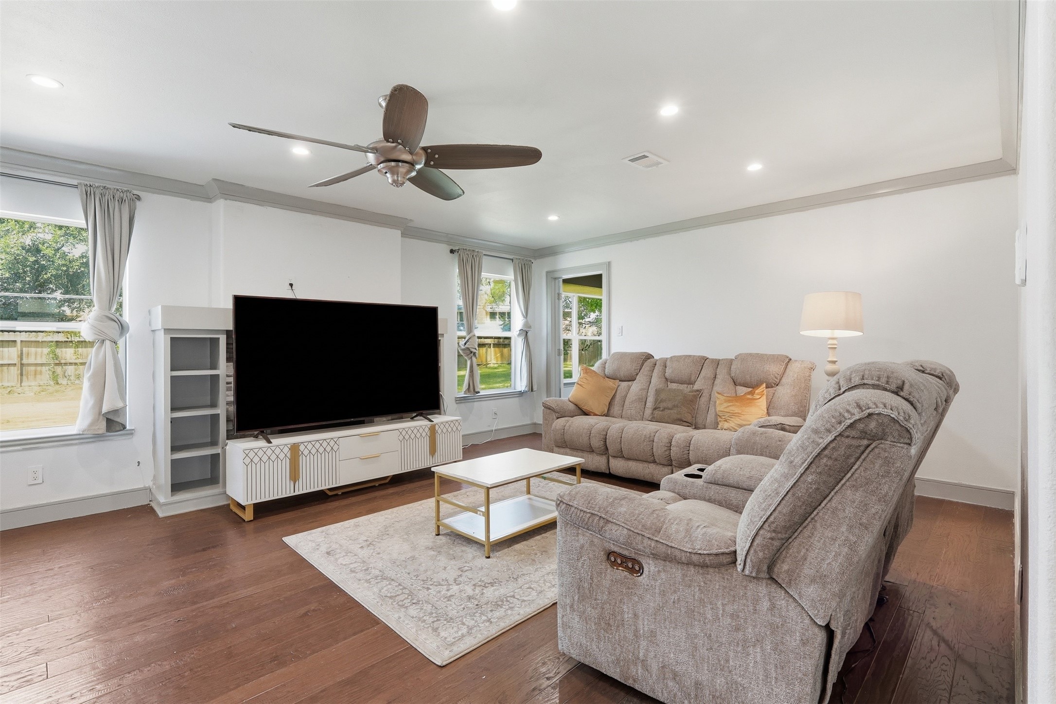 Spacious living room filled with natural light, featuring hardwood floors and direct access to the backyard.