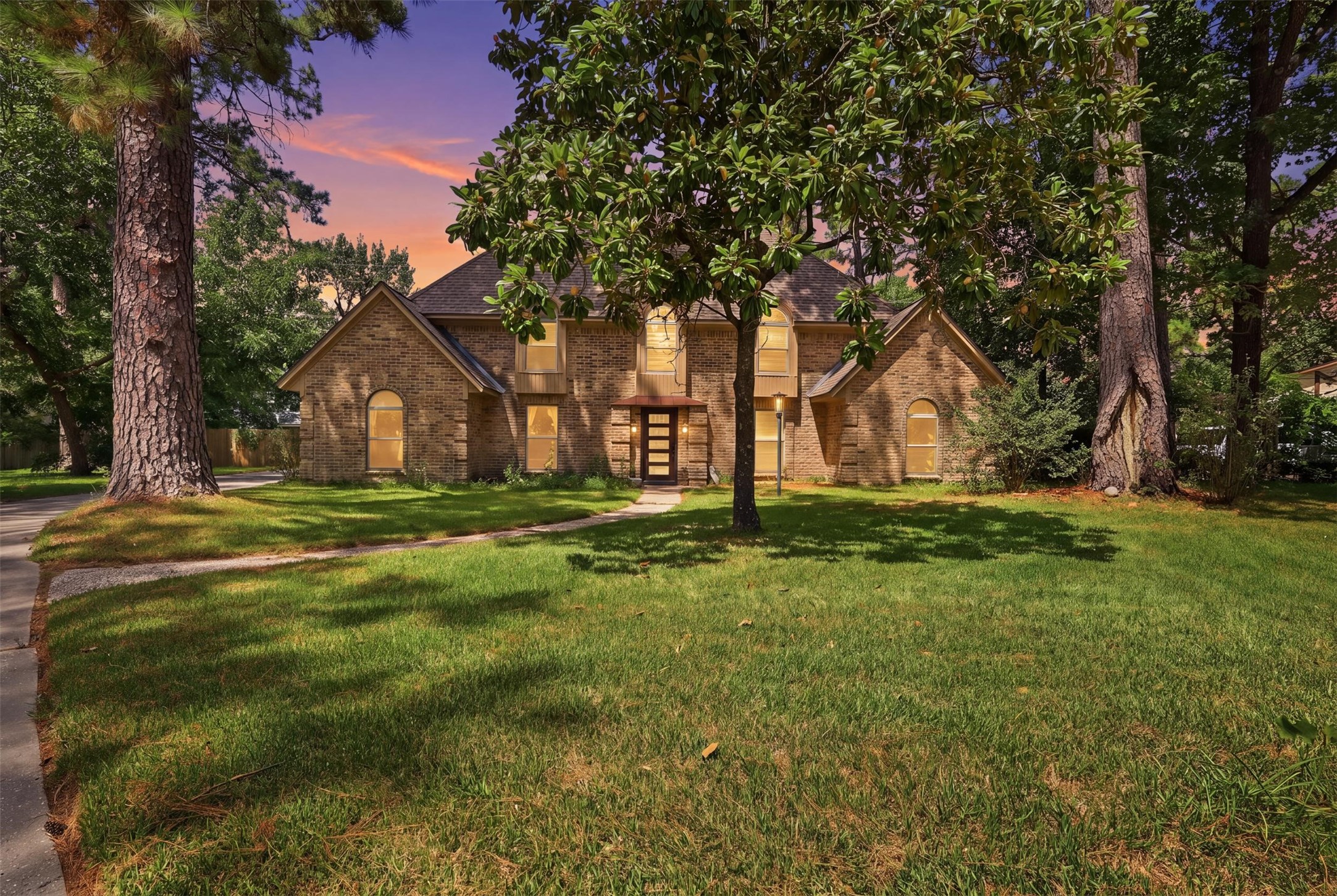 Stately brick home nestled beneath mature trees, offering timeless curb appeal and a beautiful sense of arrival.