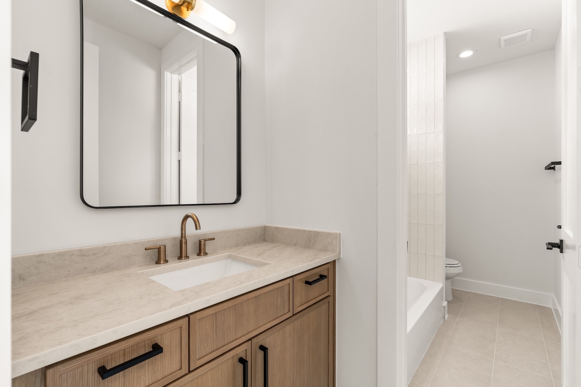 Modern hall bath featuring a stylish vanity layout and tub/shower combination.