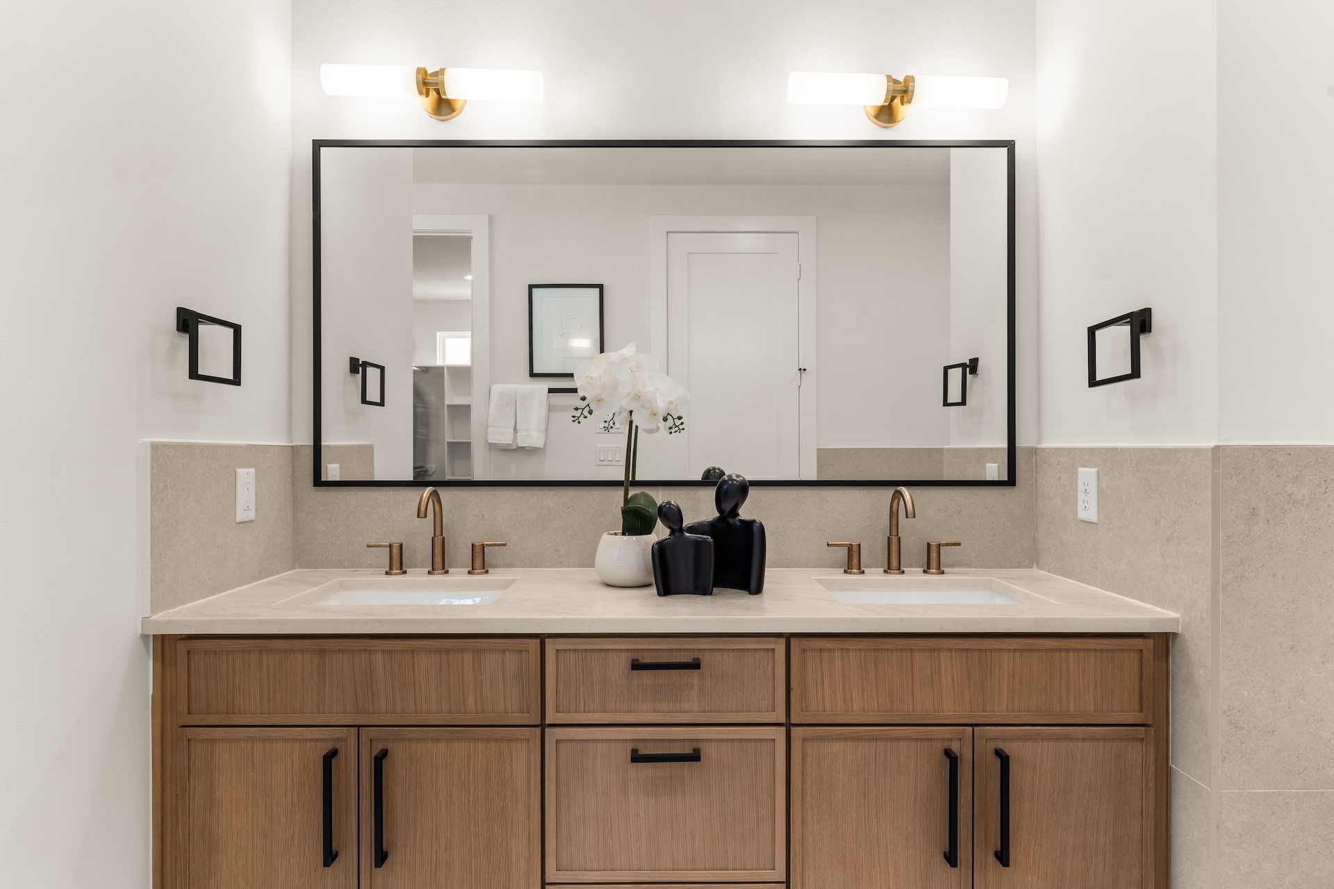 Dual undermount vanity station equipped with warm brass hardware and abundant storage.