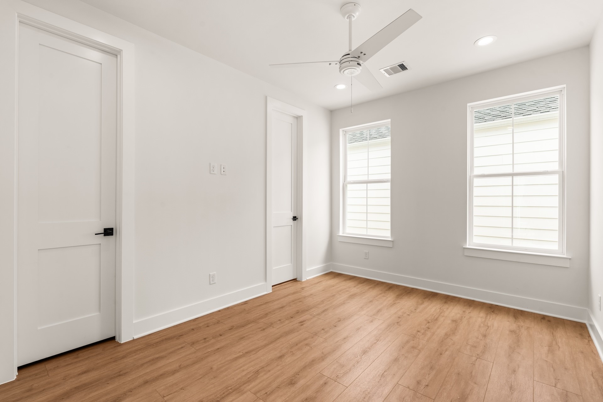 Bright secondary bedroom featuring warm wood-look flooring and sunlit views.