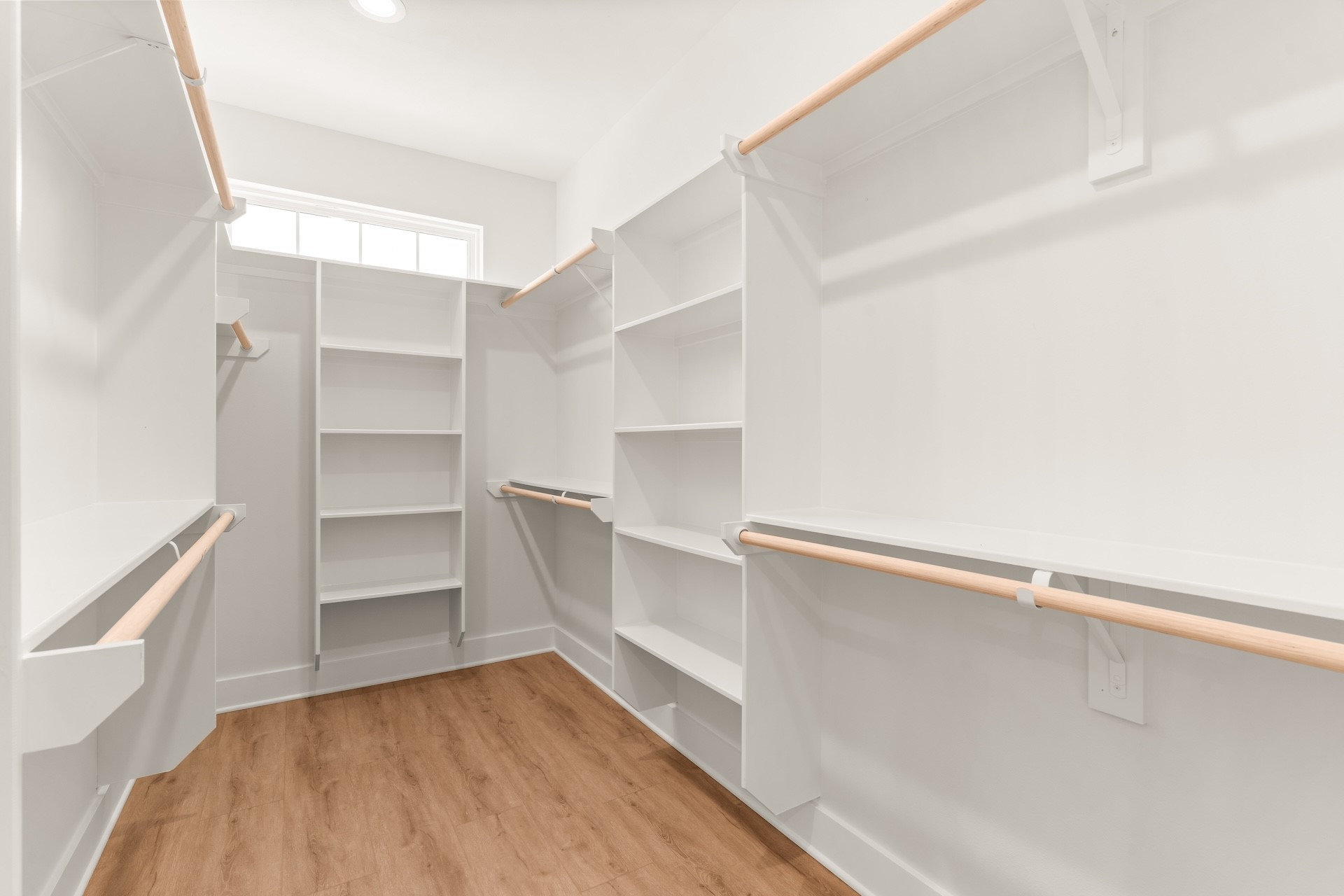 Generous walk-in primary closet complete with custom built-in shelving and hanging rods.