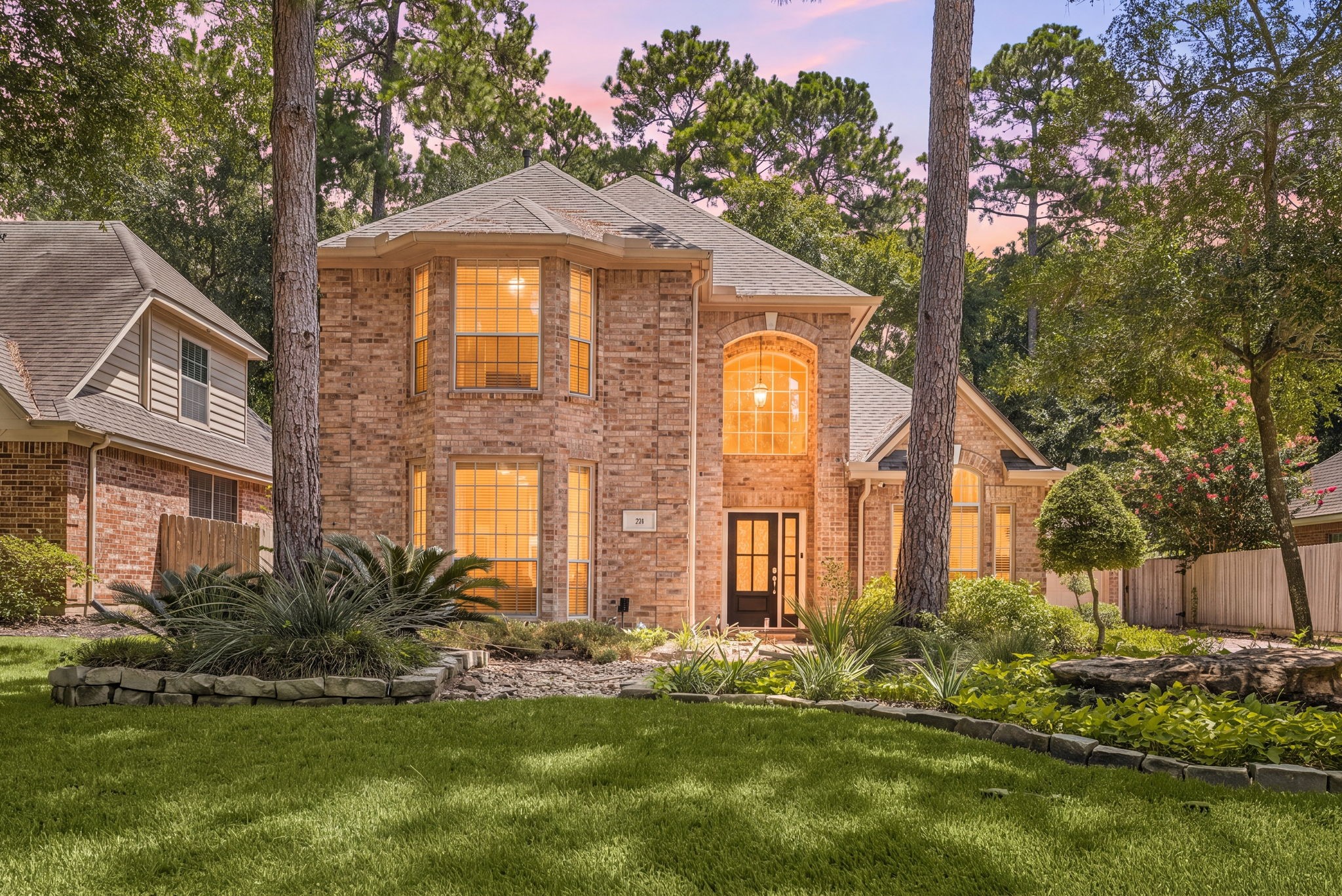 brick home with elegant arched windows, nestled among mature trees and lush landscaping. brick home with elegant arched windows, nestled among mature trees and lush landscaping.