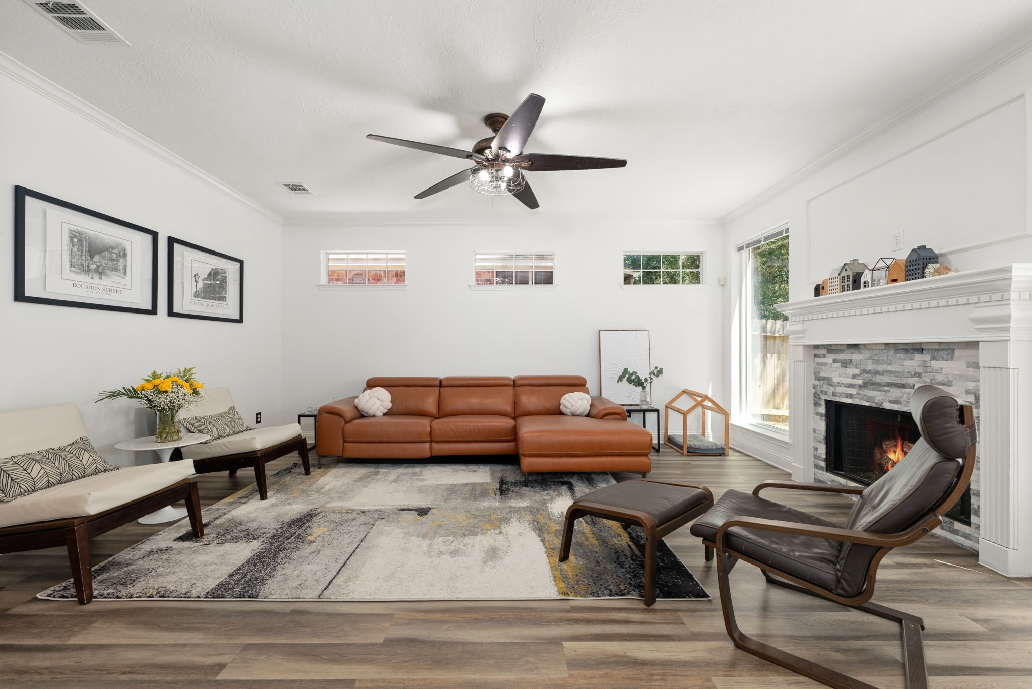 Spacious living room featuring a cozy fireplace, elegant wood fllooring, and abundant natural light from large windows.