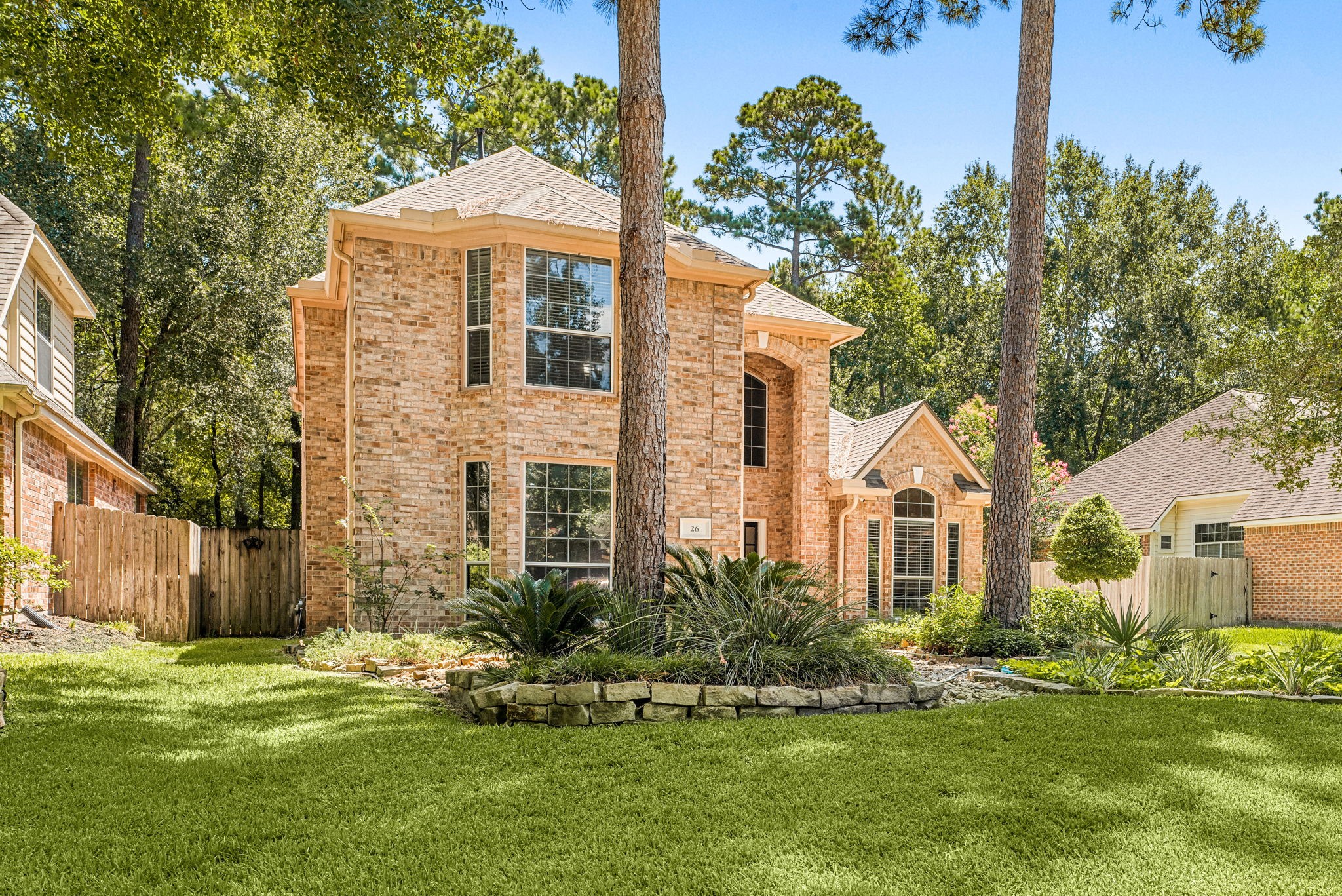 brick home with elegant arched windows, nestled among mature trees and lush landscaping.