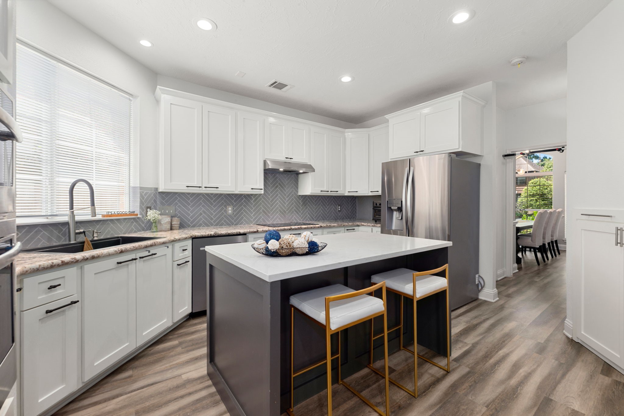Modern kitchen featuring sleek white cabinetry, stainless steel appliances, and stylish island.