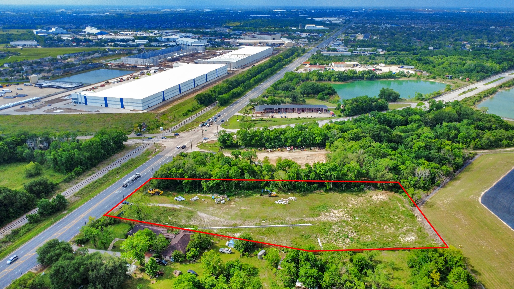 This aerial photo shows a large, irregularly shaped plot of land bordered by trees, with a road along one side. The area is mostly cleared, with some greenery and a few scattered items. Ideal for development or a spacious home site. This aerial photo shows a large, irregularly shaped plot of land bordered by trees, with a road along one side. The area is mostly cleared, with some greenery and a few scattered items. Ideal for development or a spacious home site.