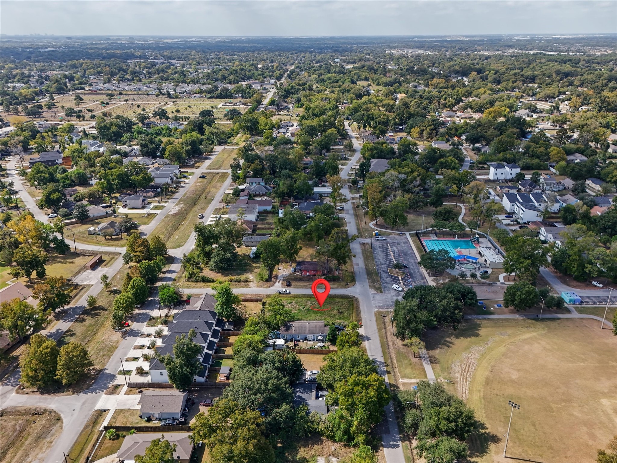 Aerial view highlighting the property's location, identified by the red marker. Conveniently situated within an established neighborhood, the property offers easy access to nearby residential areas, community amenities, a swimming pool, recreational facilities, and green spaces. This bird's-eye view showcases the property's location and surrounding community.
