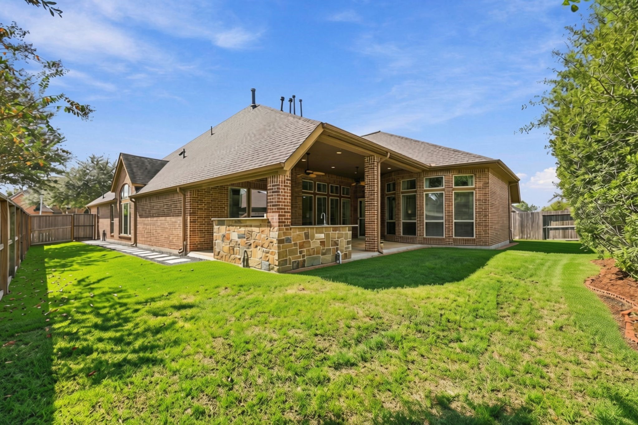 This view from the rear of the Backyard looks back toward the Covered Patio, showcasing the generous outdoor space and additional side yard. Convenient stepping stones provide an easy pathway from the Patio to the front yard, adding both functionality and accessibility to the outdoor areas.