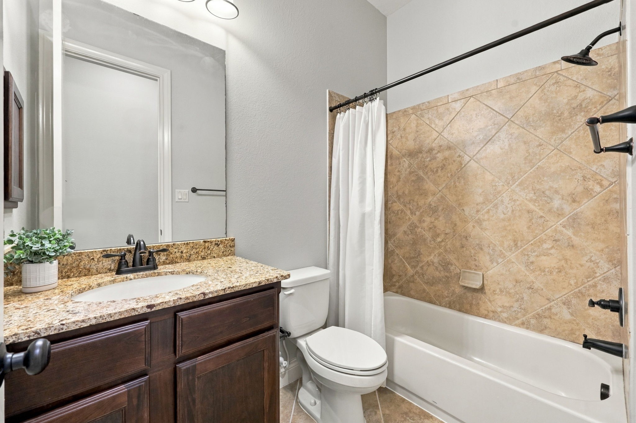 This Full Bathroom serves Bedroom #4, shown in the previous photo, and features granite countertops, an undermount sink, and beautiful espresso-colored cabinetry. Oil-rubbed bronze fixtures and coordinating lighting add a touch of elegance, while the tub and shower combination includes a built-in soap dish for added convenience.