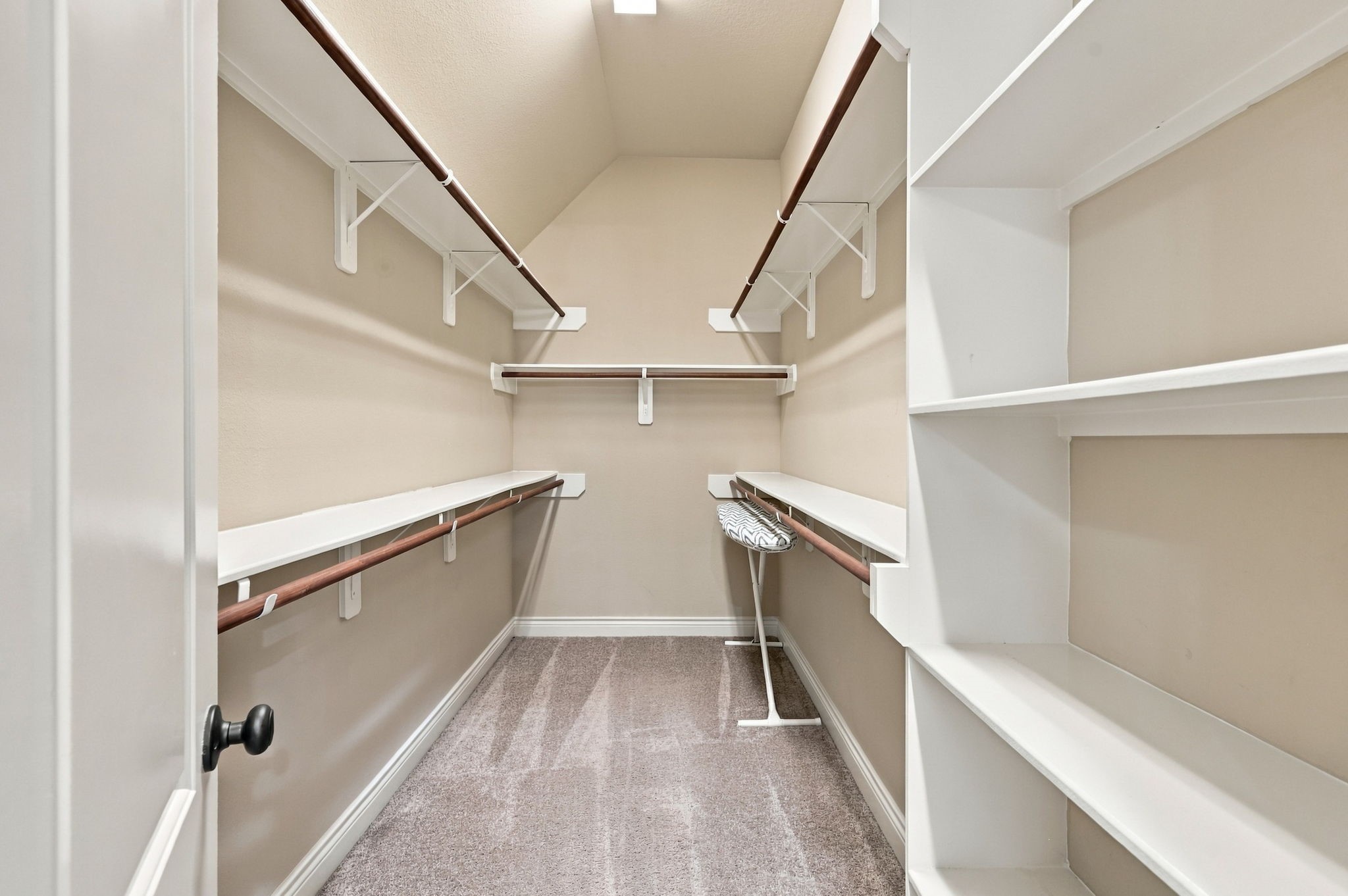 The Primary Bathroom offers two separate walk-in closets for added storage and organization. This spacious closet is one of the two, providing plenty of room for clothing, shoes, and accessories.