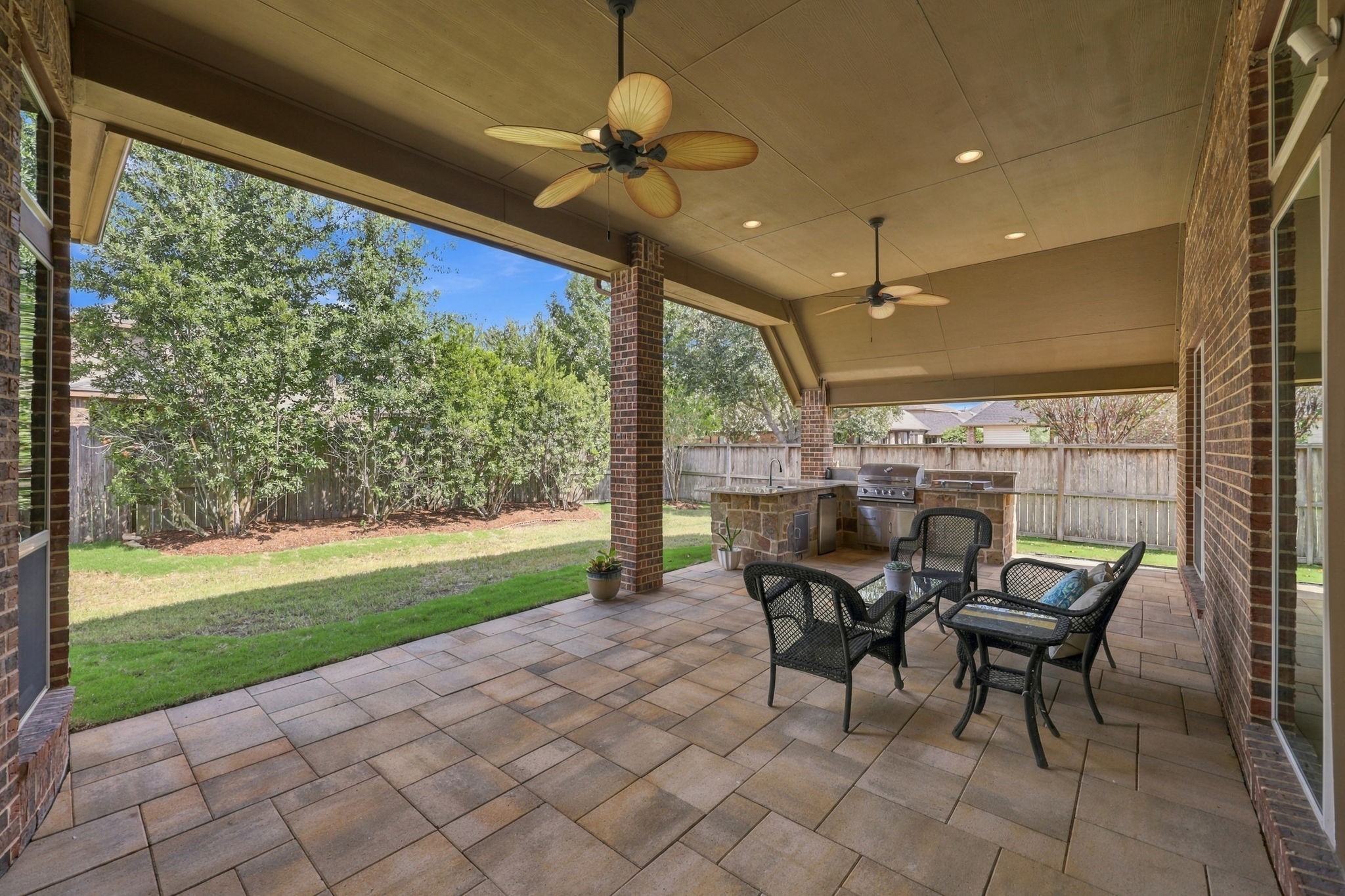 Let's step outside to the gorgeous Covered Back Patio, featuring beautiful flagstone flooring and a built-in Summer Kitchen. This inviting outdoor living space is perfect for grilling, entertaining guests, or simply relaxing and enjoying the privacy of your backyard.