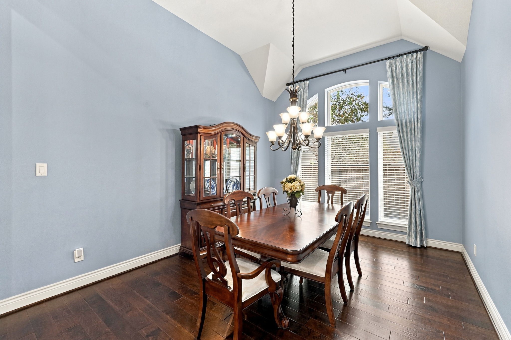 The spacious Formal Dining room easily accommodates a table seating eight or more, with plenty of additional room for a sideboard or buffet table and a china cabinet. A wall of windows dressed with designer draperies and 2-inch blinds brings in natural light while adding a touch of elegance. Perfect for hosting holiday gatherings, dinner parties, and special occasions, this inviting space offers both style and functionality. The spacious Formal Dining room easily accommodates a table seating eight or more, with plenty of additional room for a sideboard or buffet table and a china cabinet. A wall of windows dressed with designer draperies and 2-inch blinds brings in natural light while adding a touch of elegance. Perfect for hosting holiday gatherings, dinner parties, and special occasions, this inviting space offers both style and functionality.
