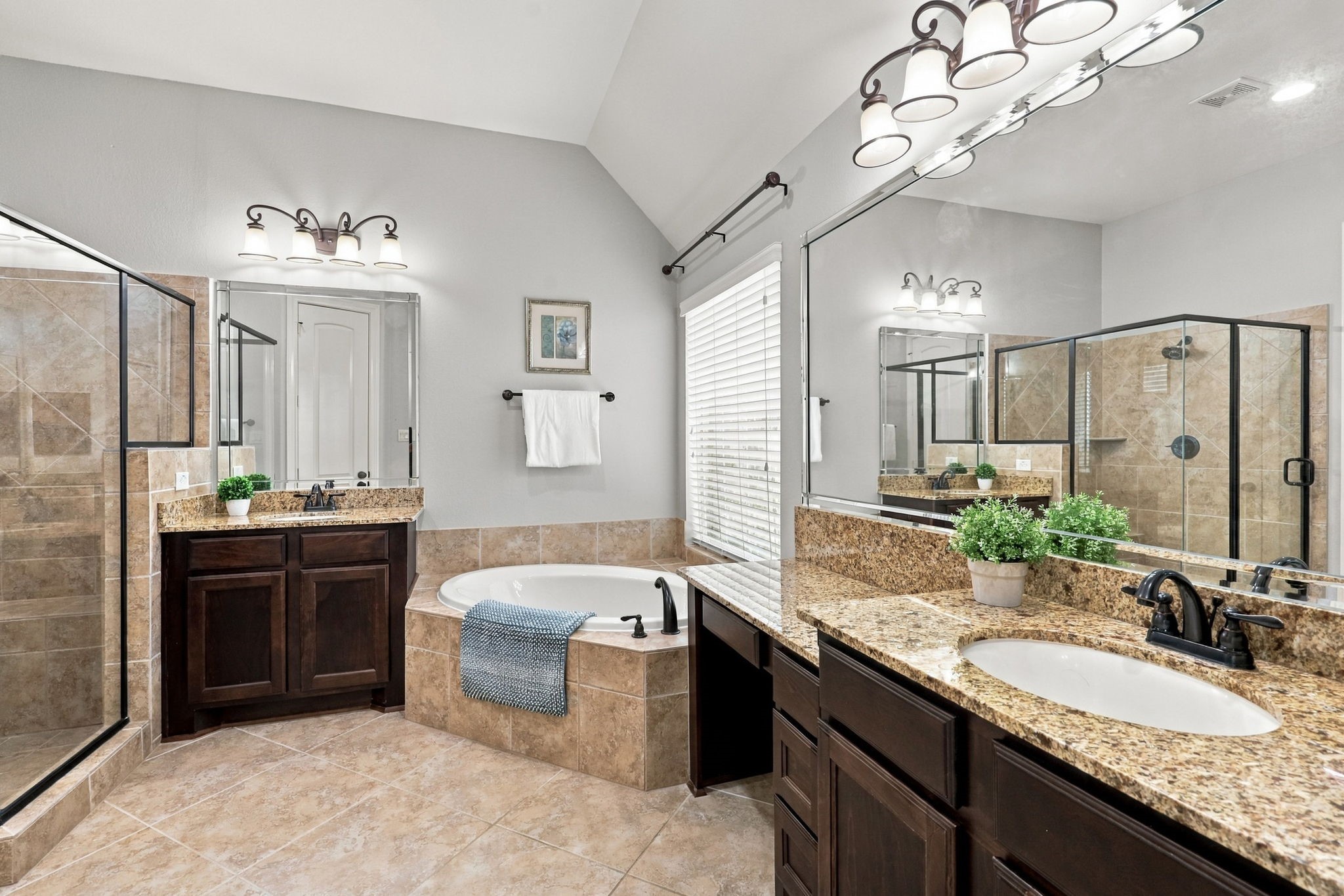The spacious Primary Bathroom features dual vanities with granite countertops, undermount sinks, and oil-rubbed bronze fixtures and faucets. A corner soaking tub adds a relaxing touch, creating the perfect spot to unwind at the end of the day.