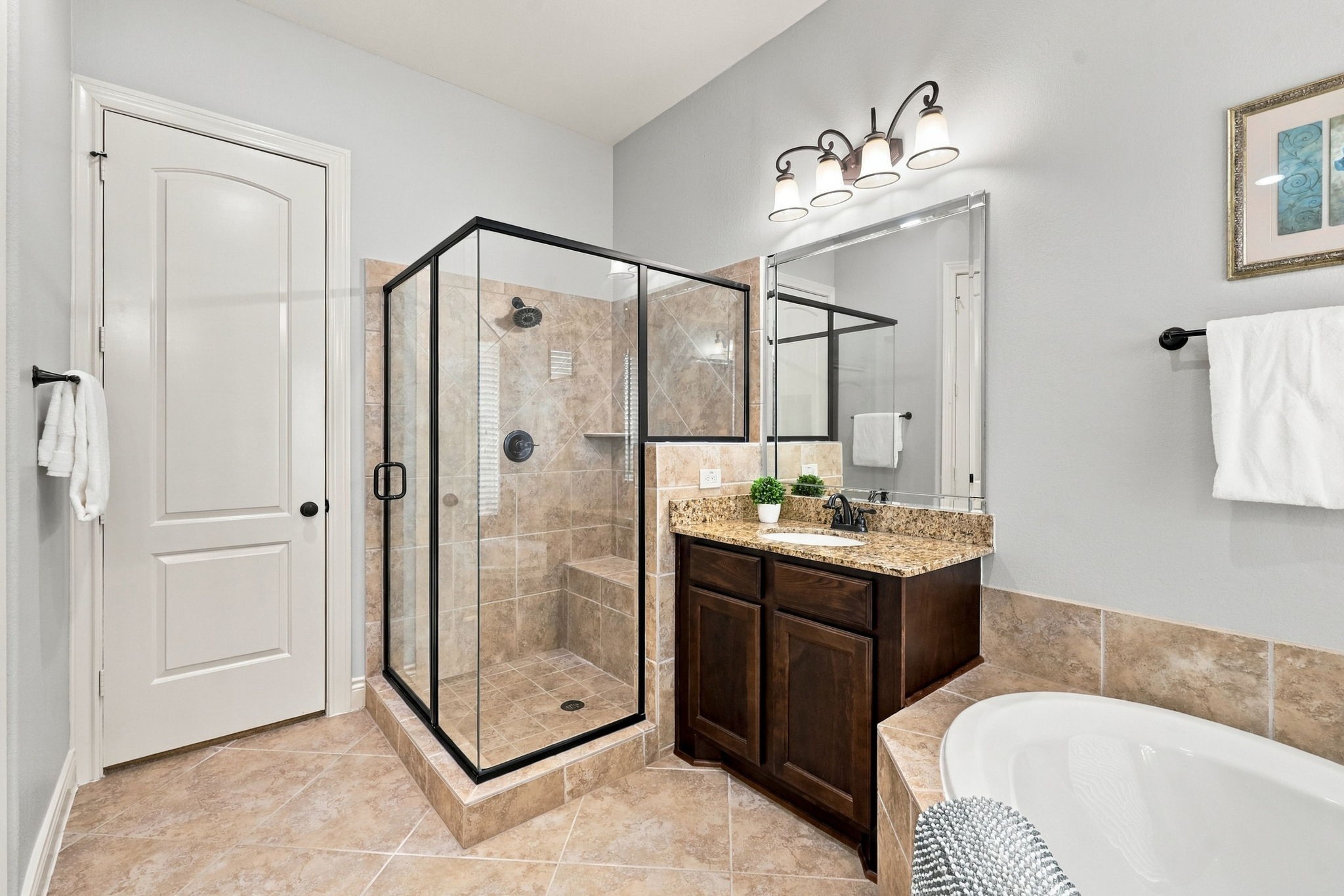This view of the Primary Bathroom highlights the second vanity, spacious walk-in shower, and the entrance to one of two walk-in closets, offering ample storage and added convenience within the private Primary Suite.