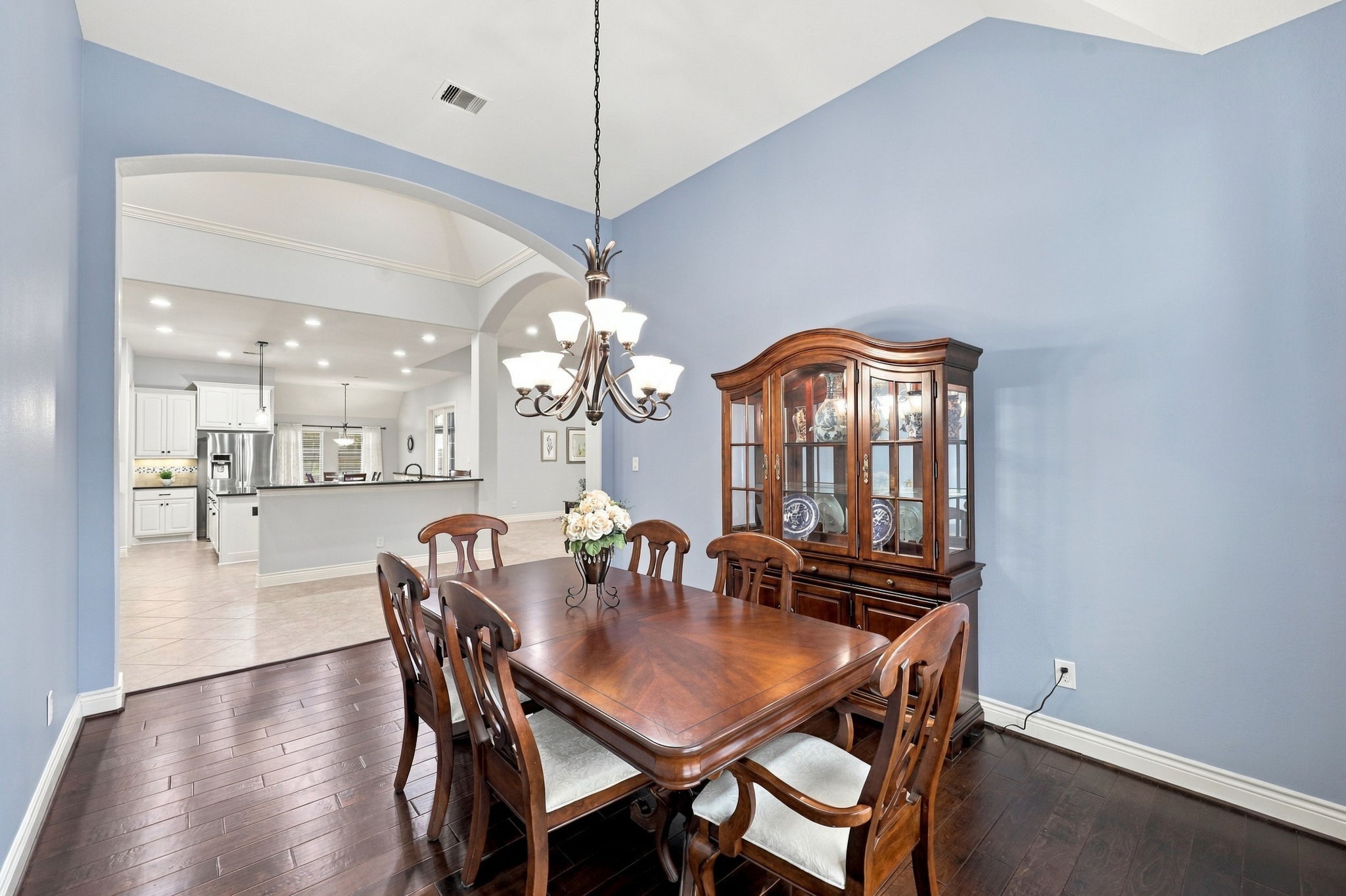 The spacious Formal Dining Room also features gorgeous wood flooring and a stunning nine-globe wrought-iron chandelier that adds elegance and character. Conveniently located directly across from the Kitchen, this room is ideal for entertaining and everyday gatherings.