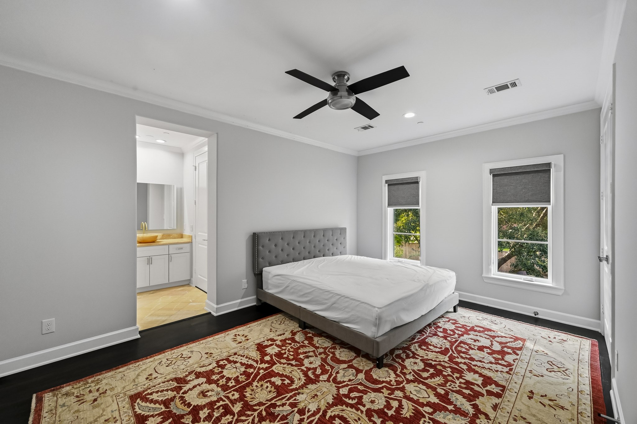 Spacious bedroom with a tall ceilings, a ceiling fan, and large windows providing ample natural light. The room features an en suite bathroom.