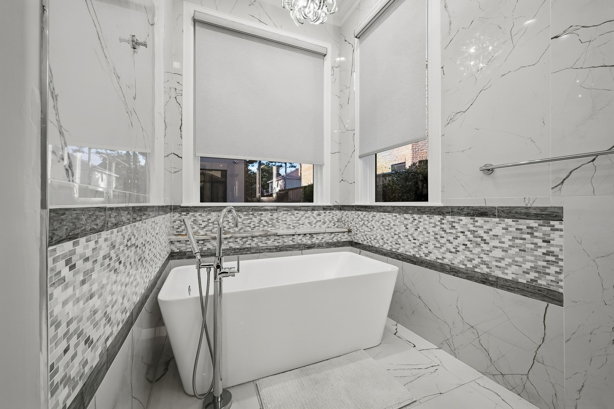 Luxurious primary bathroom featuring a modern freestanding tub, elegant walls, and stylish mosaic accents, creating a serene spa-like atmosphere.