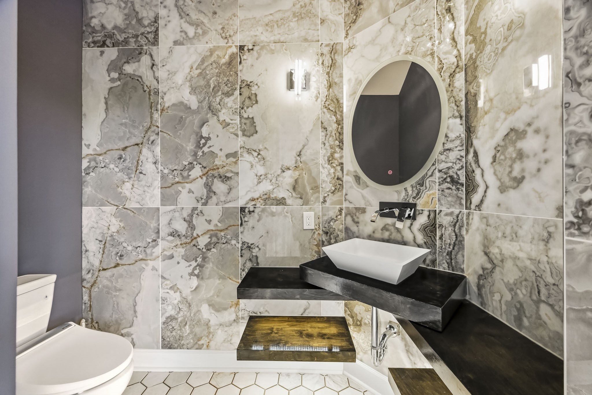 Luxurious half bathroom featuring stunning marble walls, a modern vessel sink, and sleek black fixtures, creating a sophisticated and elegant space.