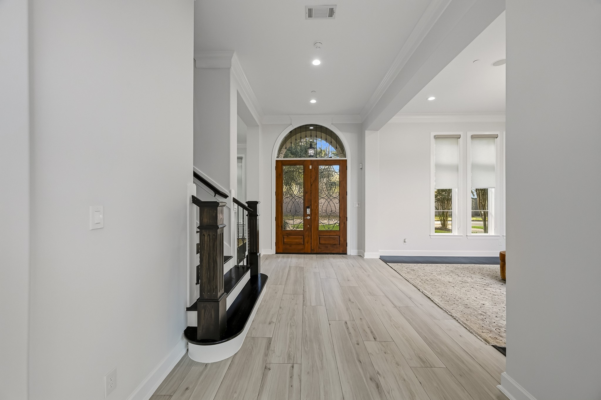Stunning entryway featuring elegant flooring, a grand arched door, and abundant natural light streaming through large windows, creating a welcoming and sophisticated atmosphere.