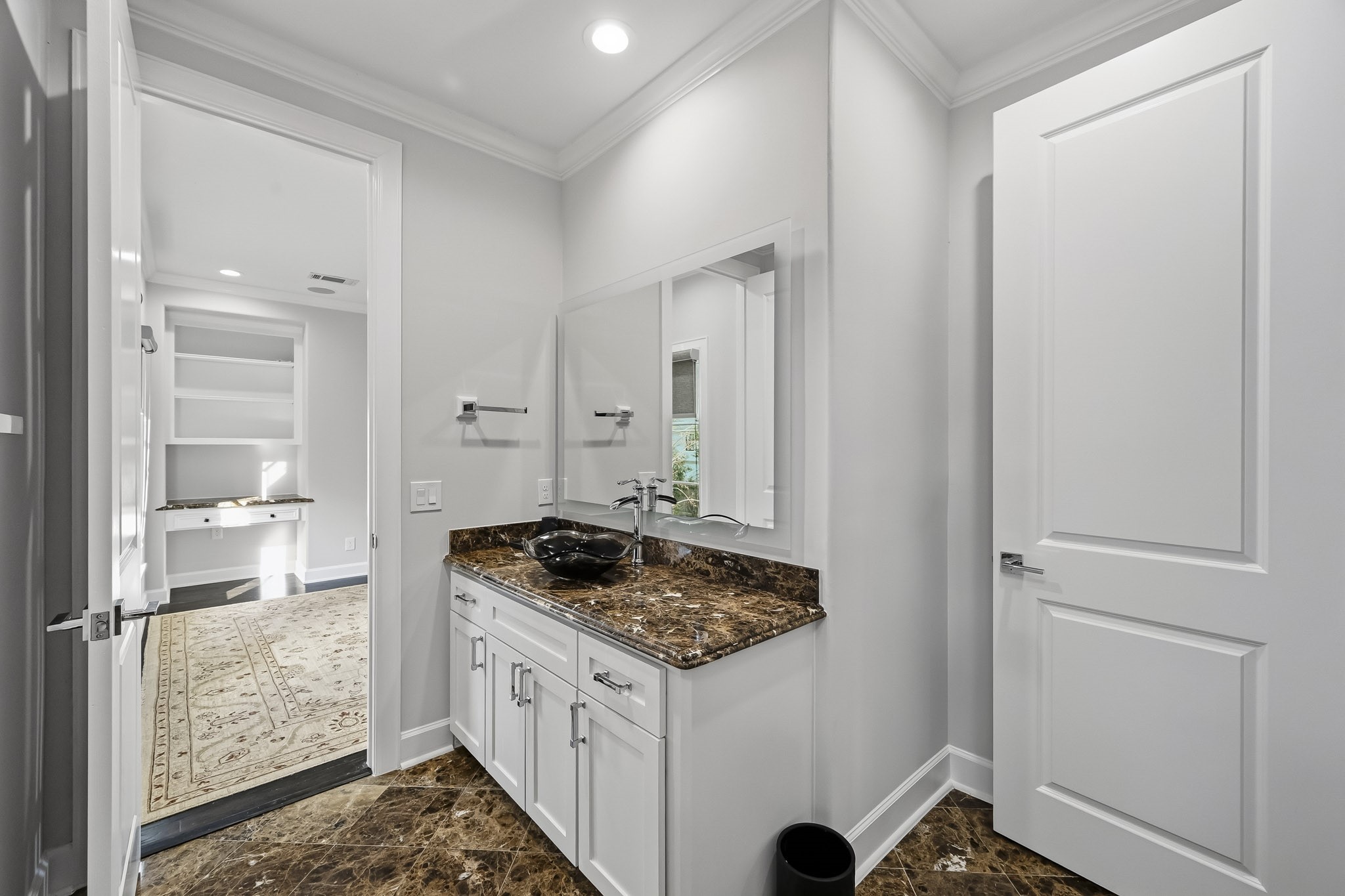 Elegant secondary bathroom featuring a sleek countertop with a stylish vessel sink, complemented by white cabinetry and modern fixtures.
