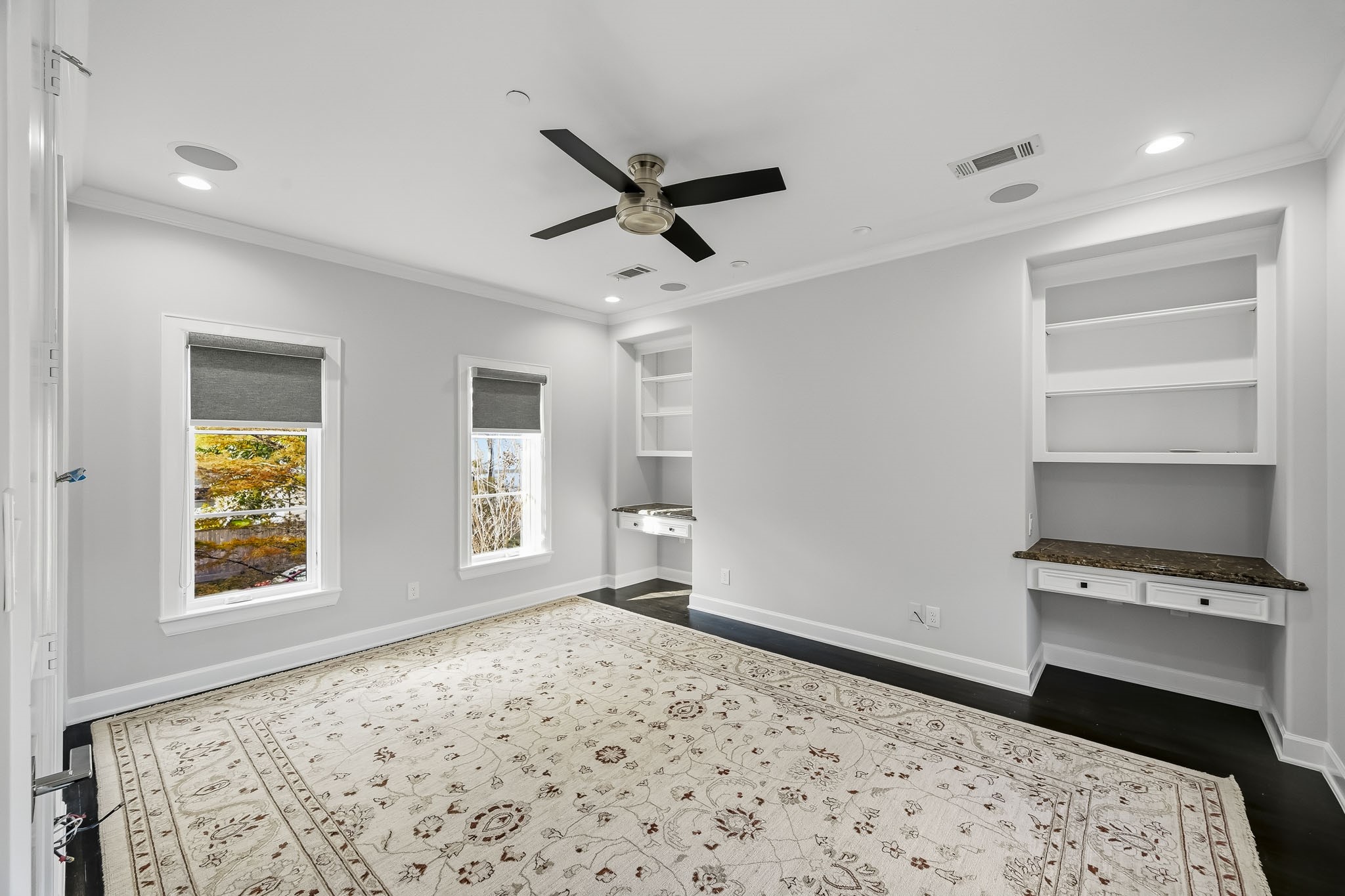 Bright and spacious bedroom featuring built-in shelving, a stylish ceiling fan, and large windows with scenic views.