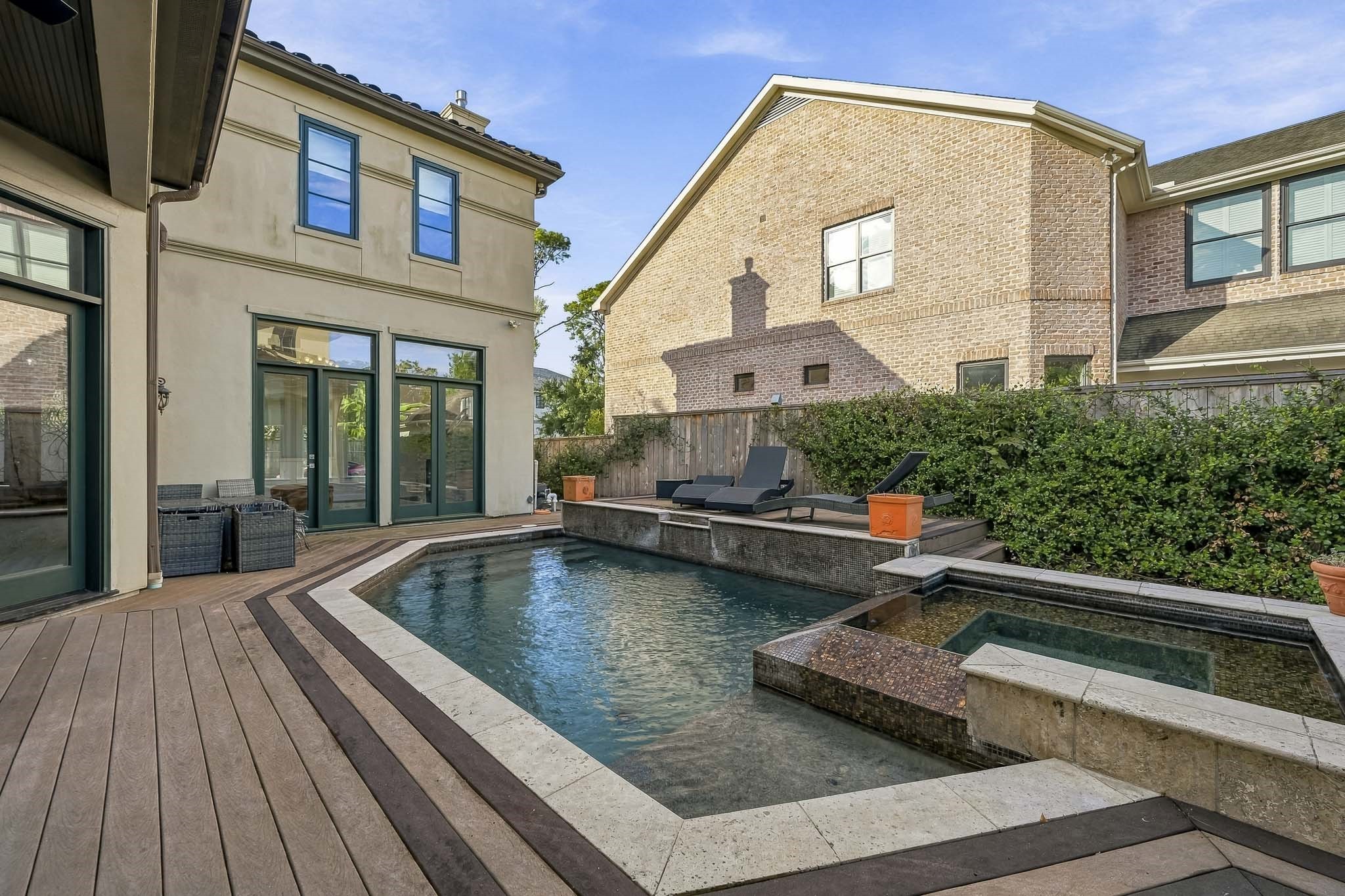 Experience luxury living with a stunning backyard featuring a sleek pool and spa, surrounded by elegant decking and lush greenery, perfect for relaxation and entertainment.