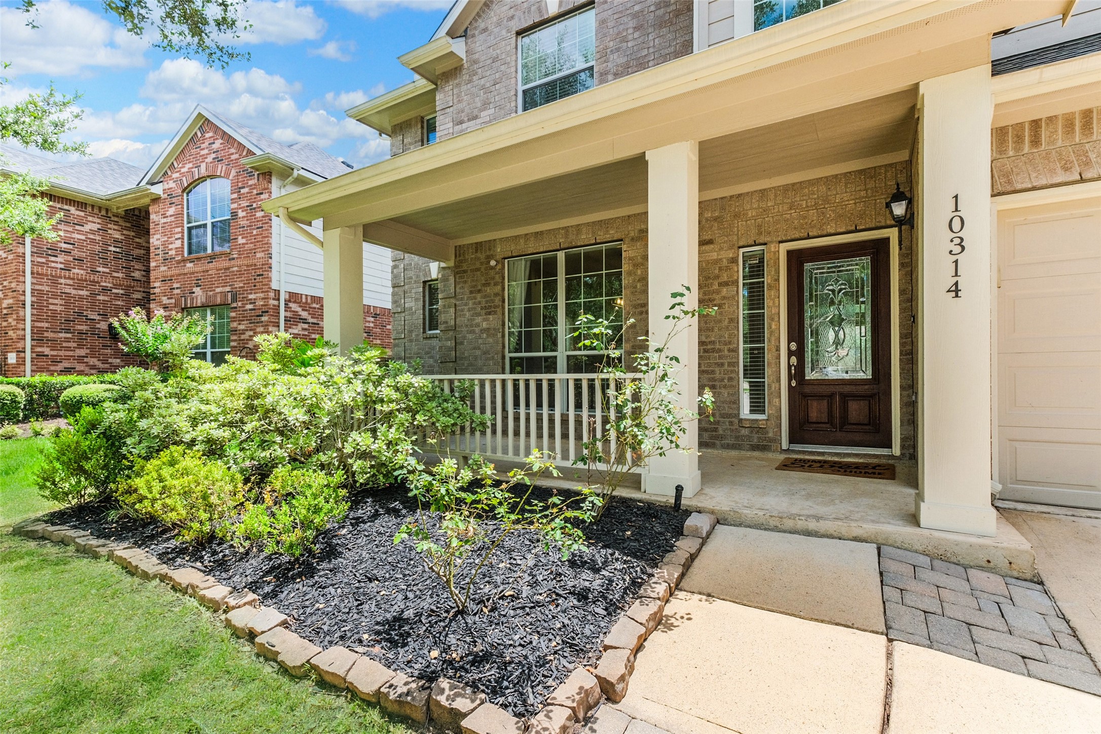 Charming front porch with brick exterior, manicured landscaping, and a welcoming entryway. Perfect for relaxing and enjoying the neighborhood view.