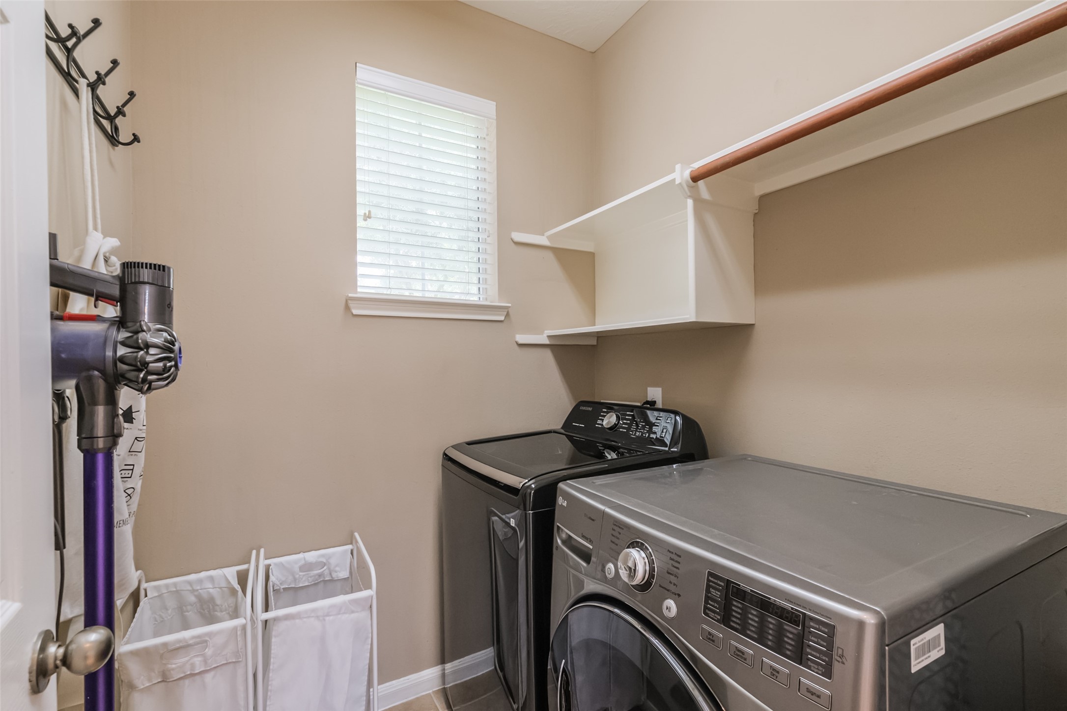 Well-organized laundry room with neutral walls, featuring a window for natural light.