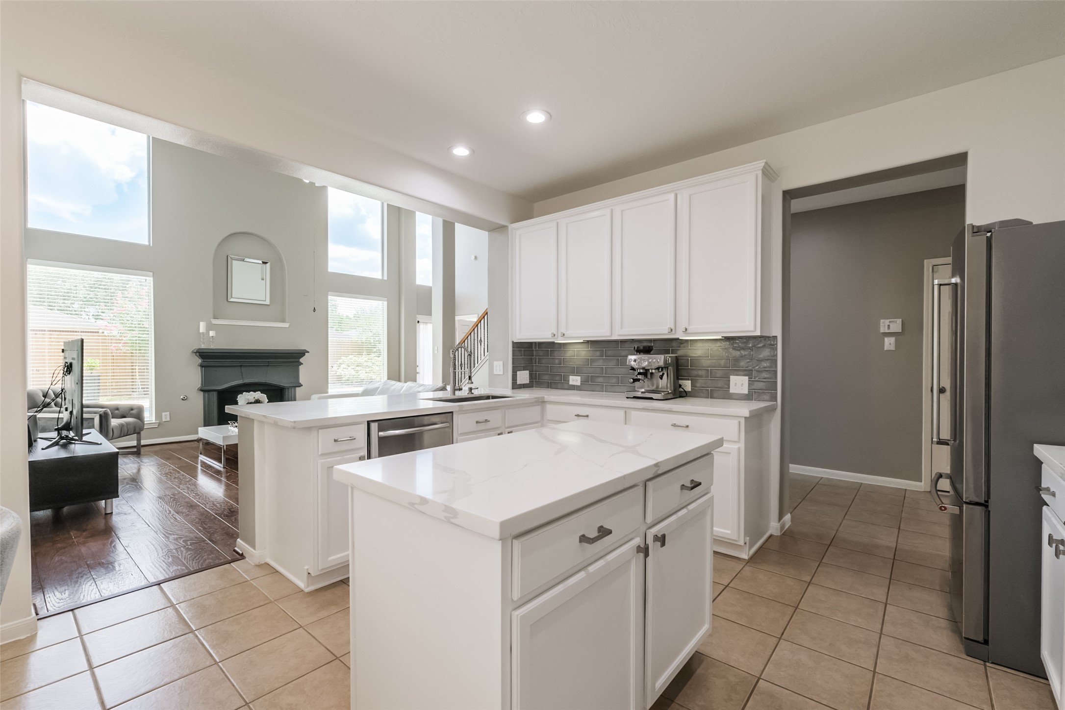 Bright, open-concept kitchen with modern white cabinetry & sleek countertops.