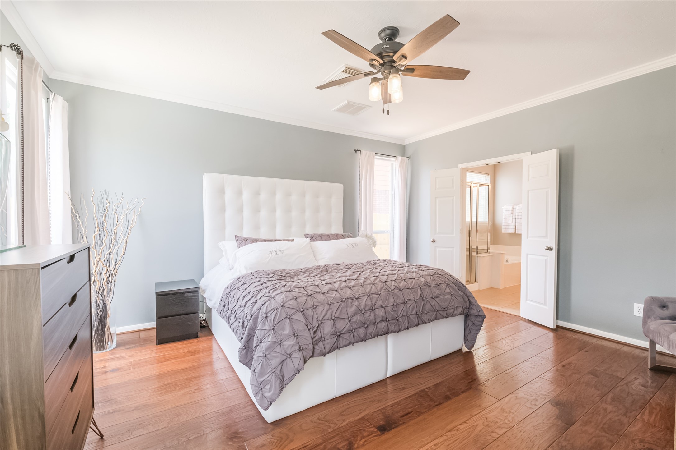 Bright and spacious primary bedroom with hardwood floors and neutral walls.
