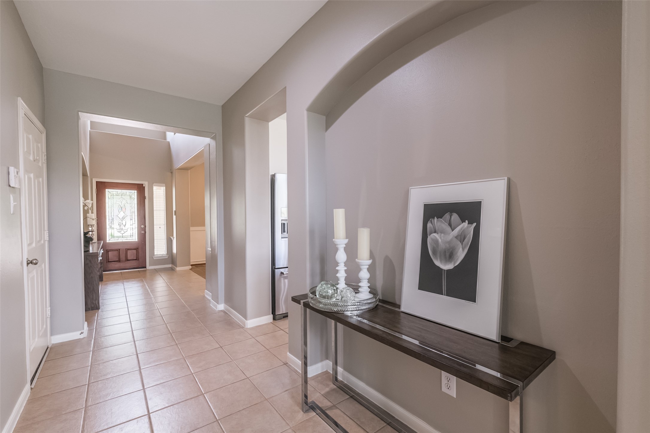 This entryway features neutral walls and tile flooring, leading to a spacious area with room for a console table.