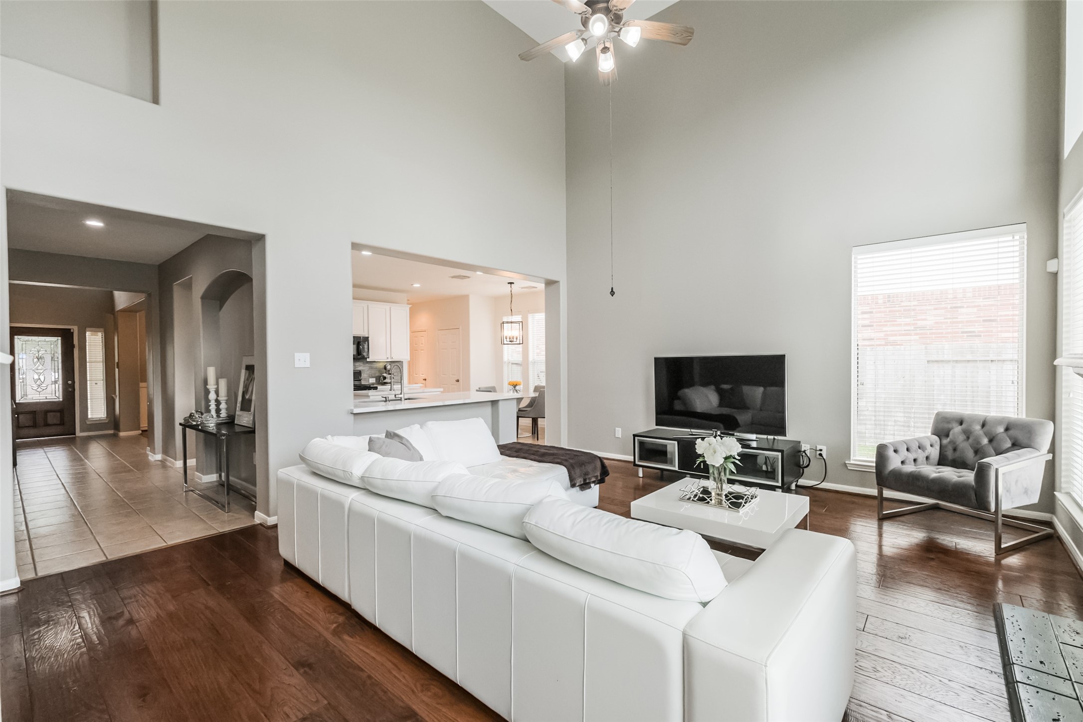 Spacious living area with high ceilings, hardwood floors, and abundant natural light. The open layout connects to the kitchen, featuring modern fixtures and straight sight lines.
