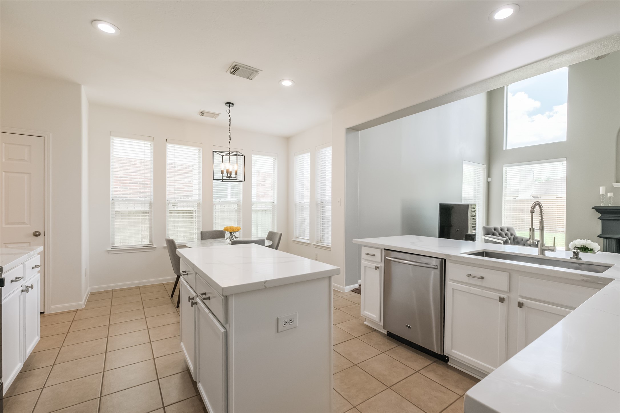 Bright and spacious kitchen with modern white cabinetry, a central island, stainless steel appliances, and large windows providing ample natural light.