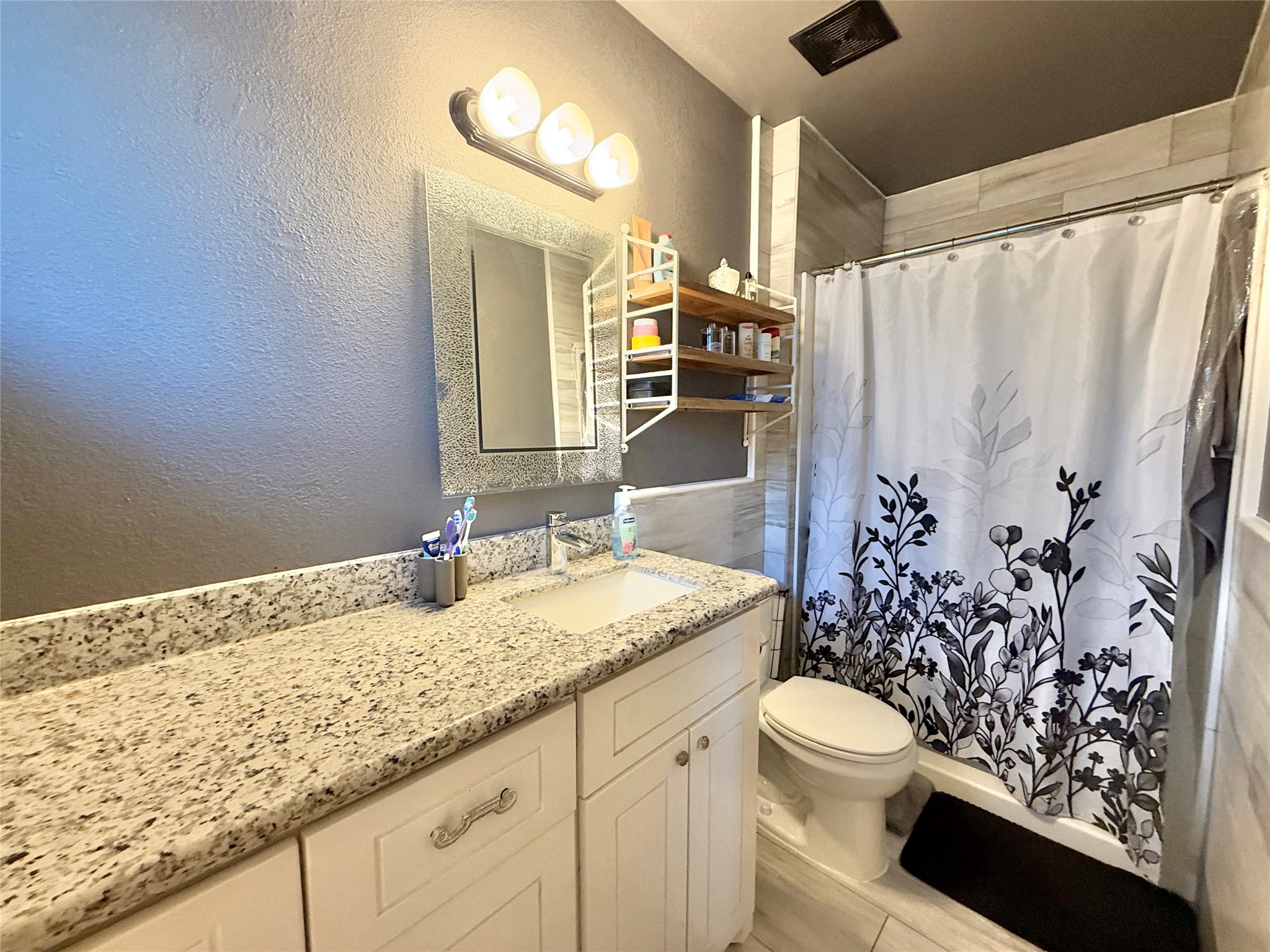 En-suite Bathroom with granite counters and floor to ceiling tile in shower and wainscoting the walls