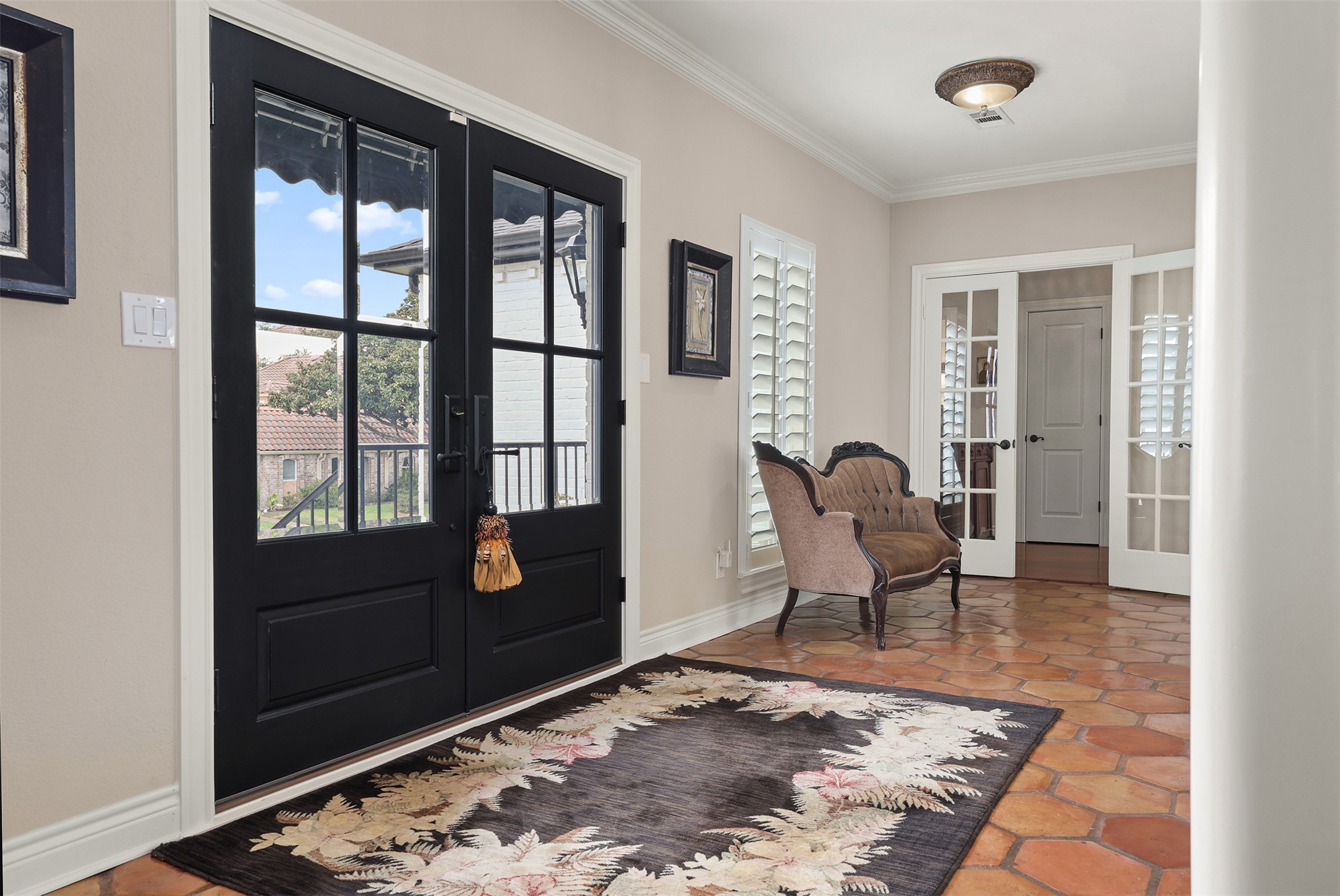 Step inside through elegant black double French doors into a welcoming foyer.