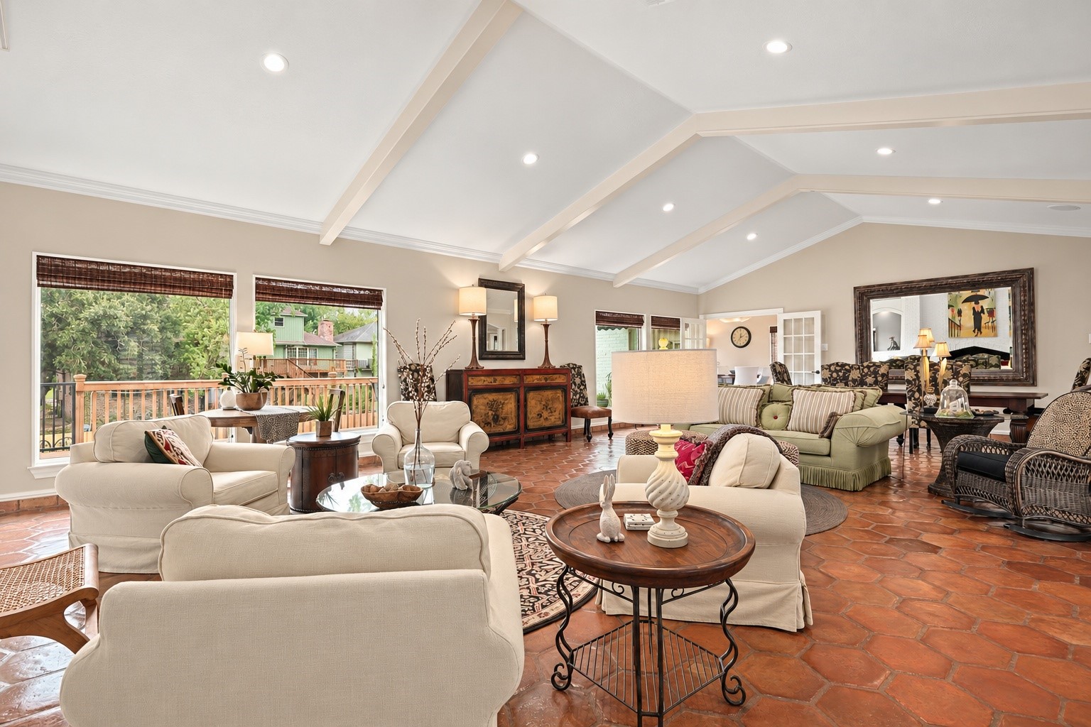 Expansive windows fill this beautiful living space with natural light, while soaring ceilings with decorative beams and a tastefully selected neutral paint palette create a warm, welcoming atmosphere.