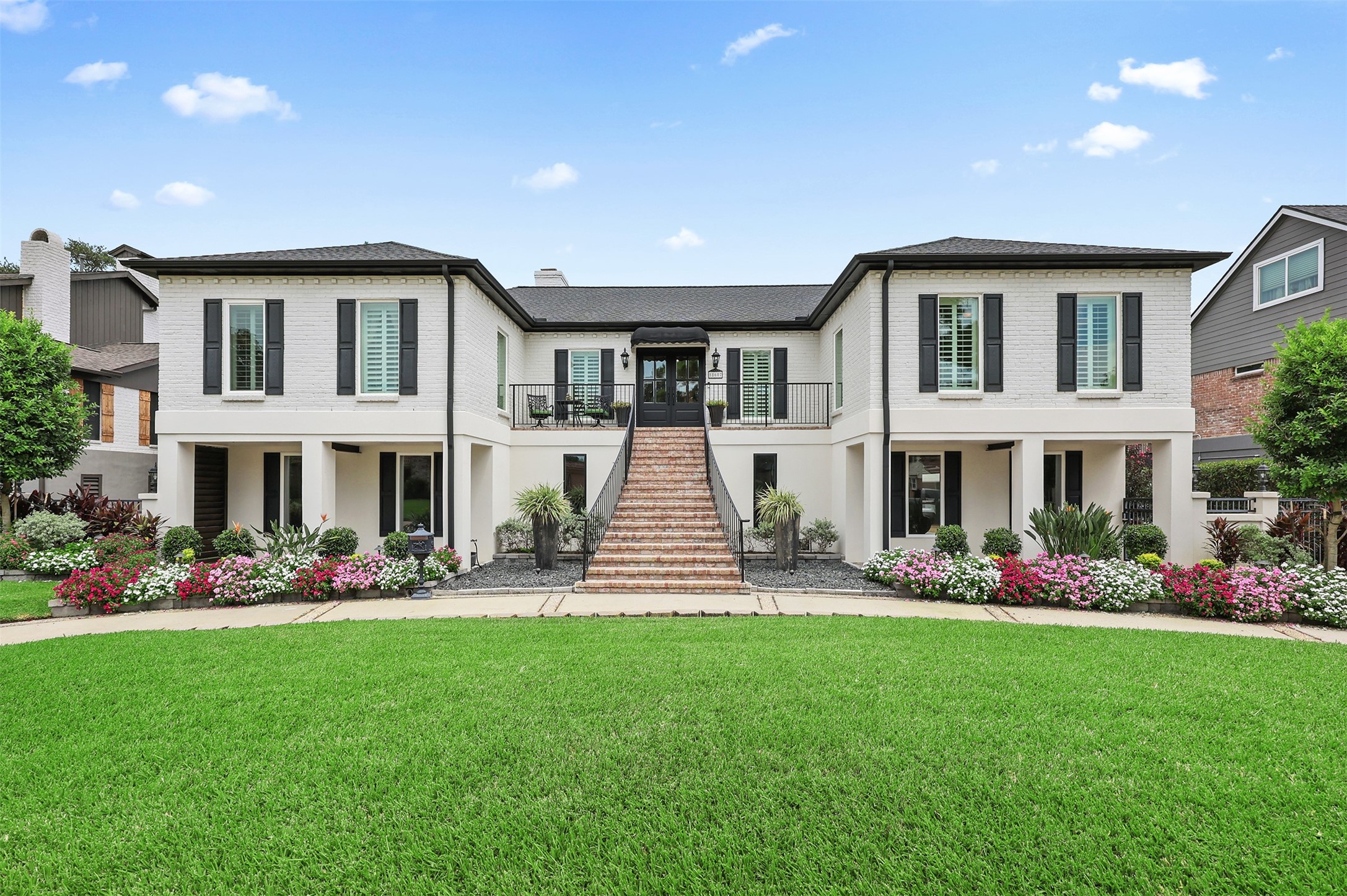 Timeless New Orleans-inspired charm! Beautifully designed with an impressive Old Chicago-style brick staircase, inviting covered porches on either side of the home, and coordinating brick pavers that complement the staircase. Classic black shutters, elegant architectural details, and lush landscaping complete this stunning exterior.
