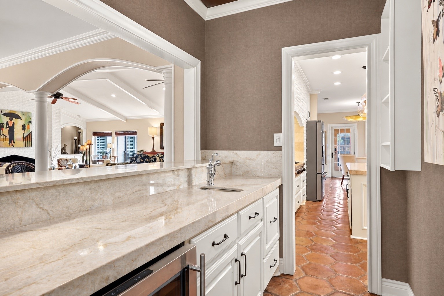 View from the television room looking through the pass-through wet bar toward the kitchen, showcasing the convenient flow between these spaces.