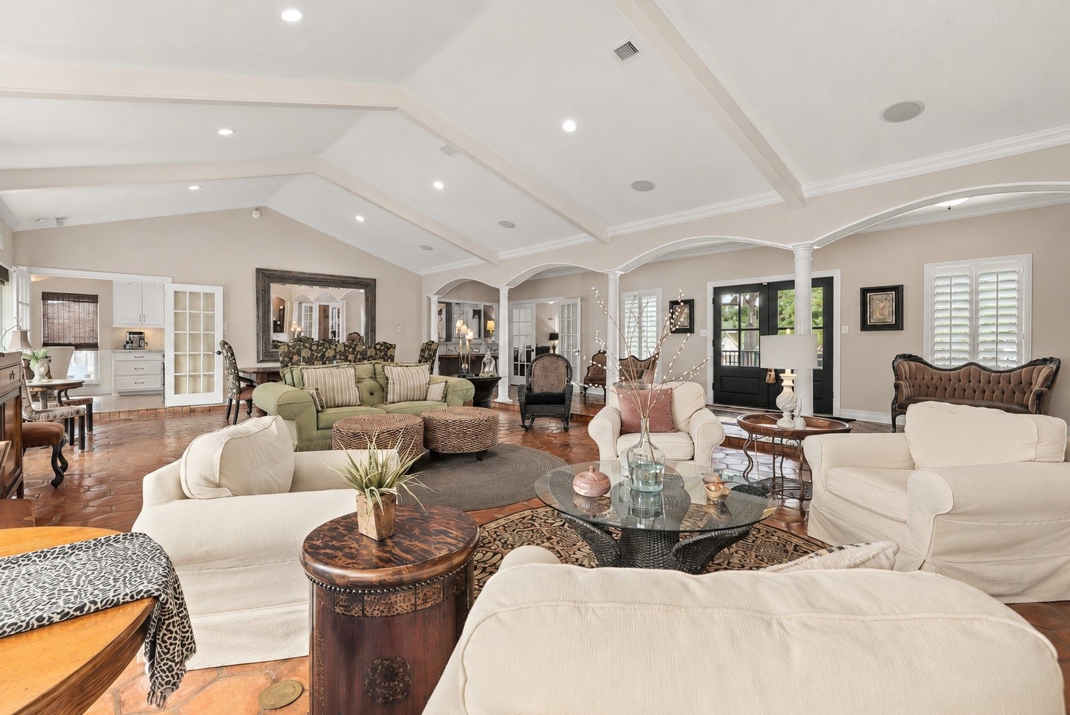 An entertainer's dream! This expansive, open-concept living area offers three distinct seating areas, beautiful architectural arches, soaring beamed ceilings, and authentic octagonal Saltillo tile flooring. Enjoy an easy flow to the kitchen through French doors, with a convenient wet bar and separate television room nearby. Updated front entry doors complete with warm and inviting space, perfect for gatherings large or small.