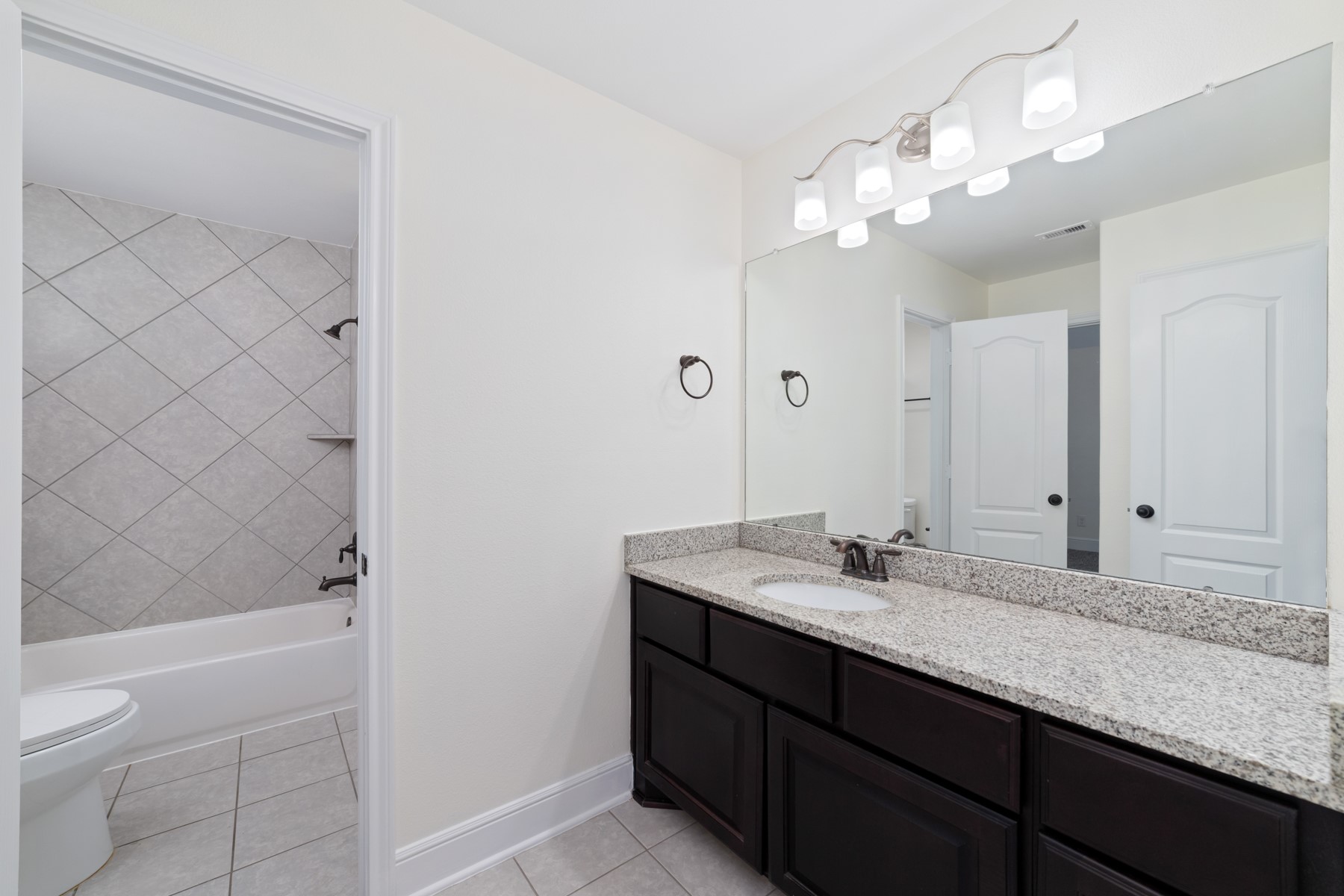 This bathroom features a modern design with dual sinks, and sleek dark cabinetry.