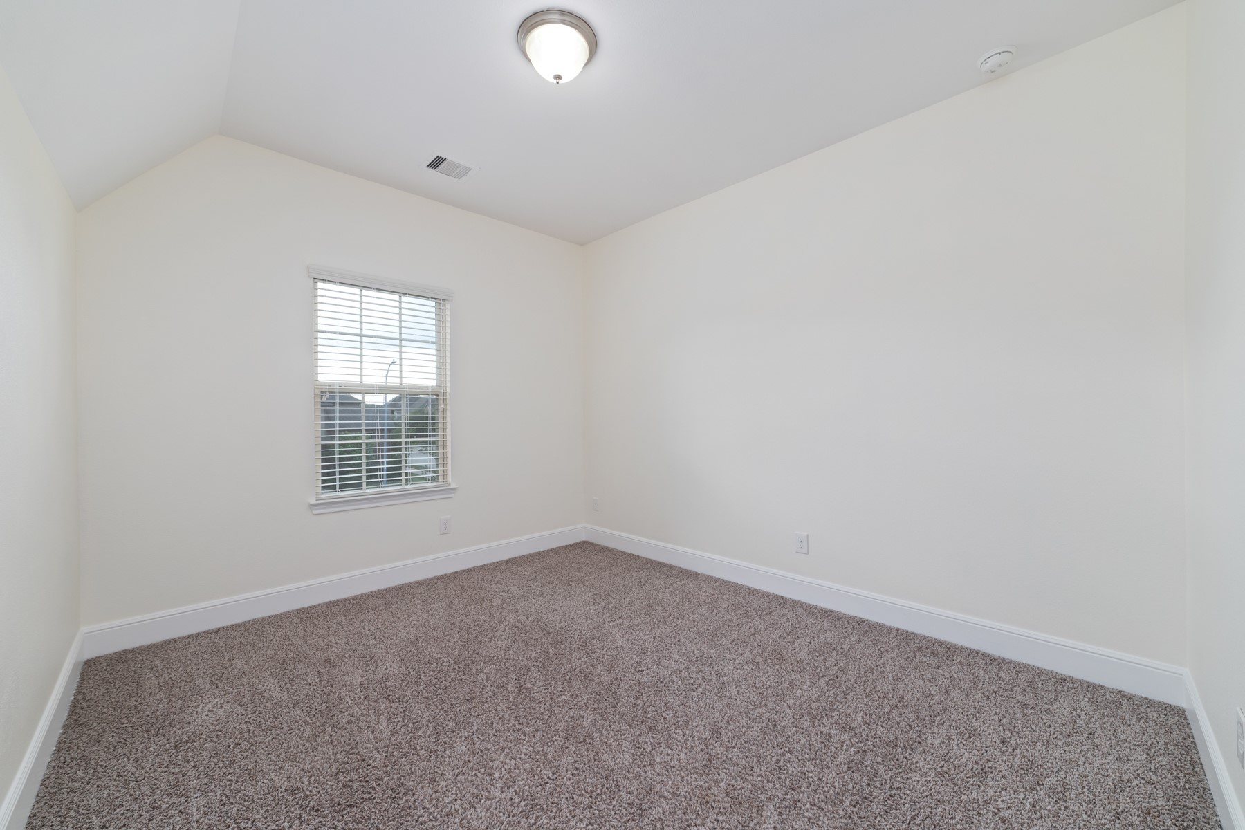 Bedroom #4 - This room features neutral walls, a plush carpet, and a single window with a decorative shade, providing a cozy and versatile space.