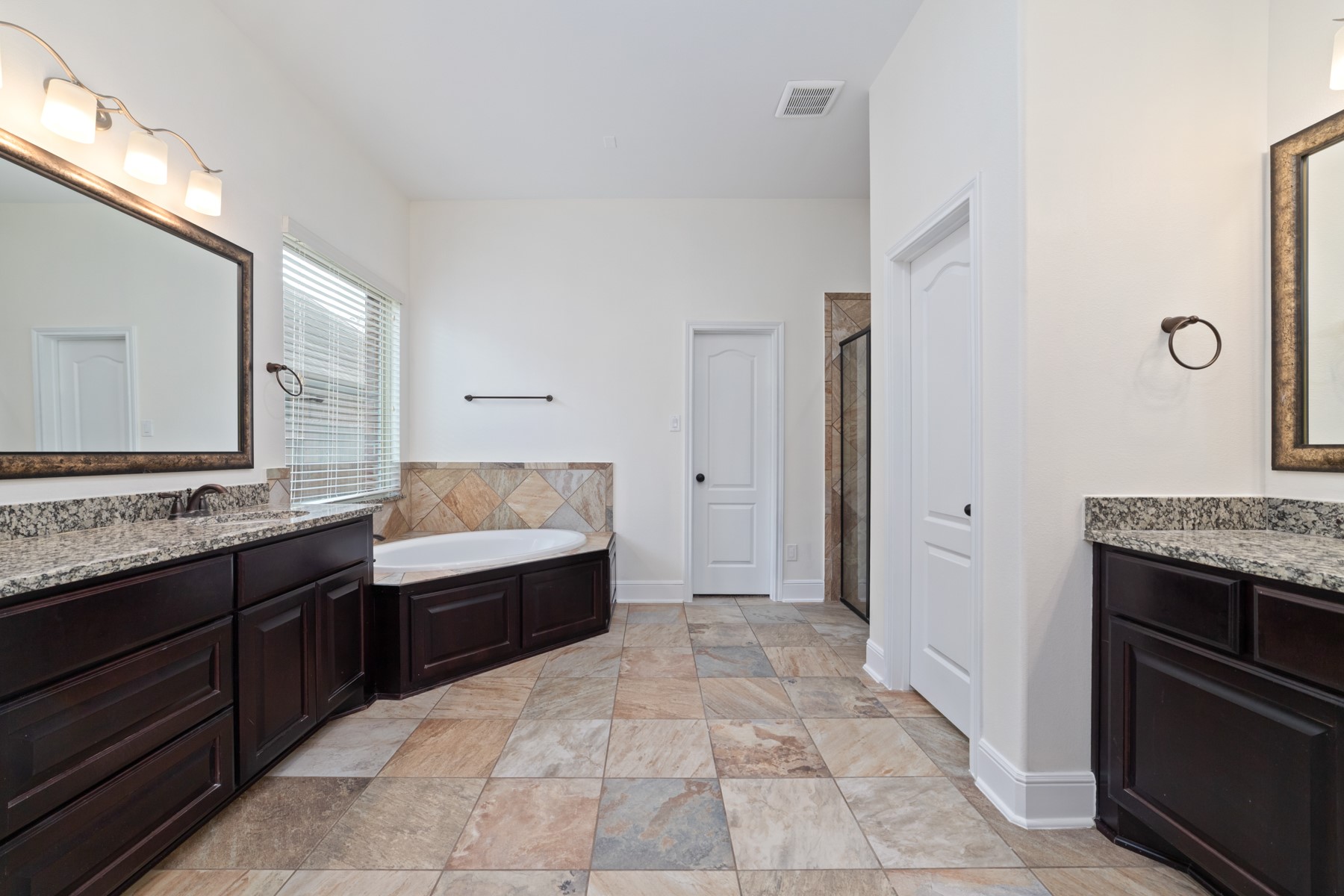 Featuring a luxurious soaking tub, elegant dark wood cabinetry, and a large window for natural light.