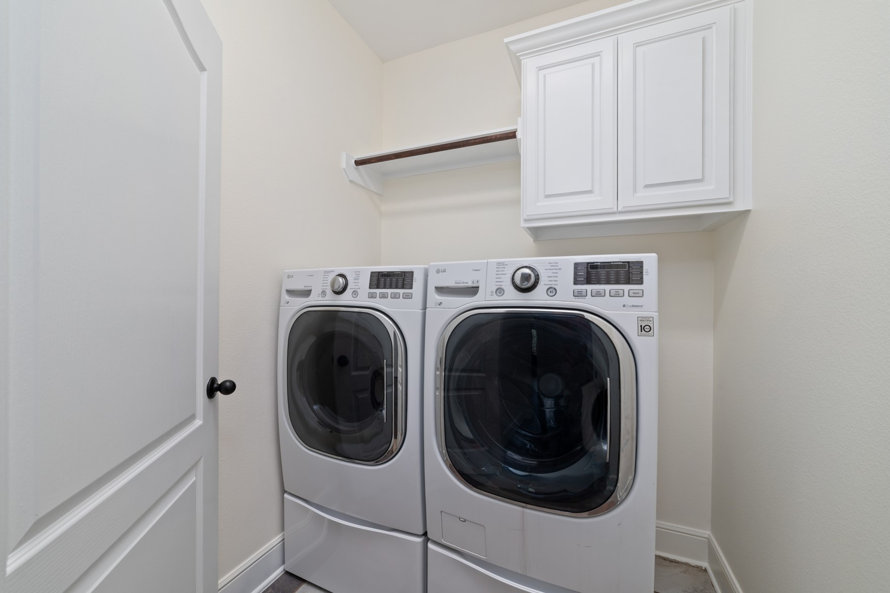 This laundry room with a shelf above for storage and a cabinet for additional storage space. Washer and dryer included