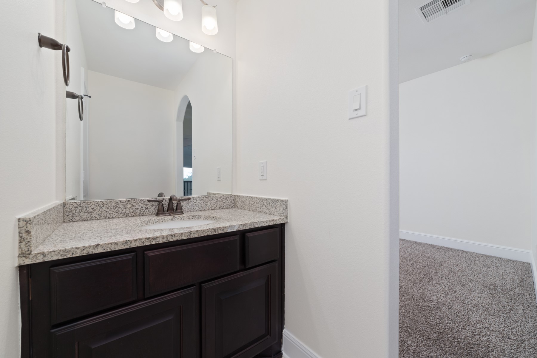 This modern bathroom features bronze fixtures, and overhead lighting.